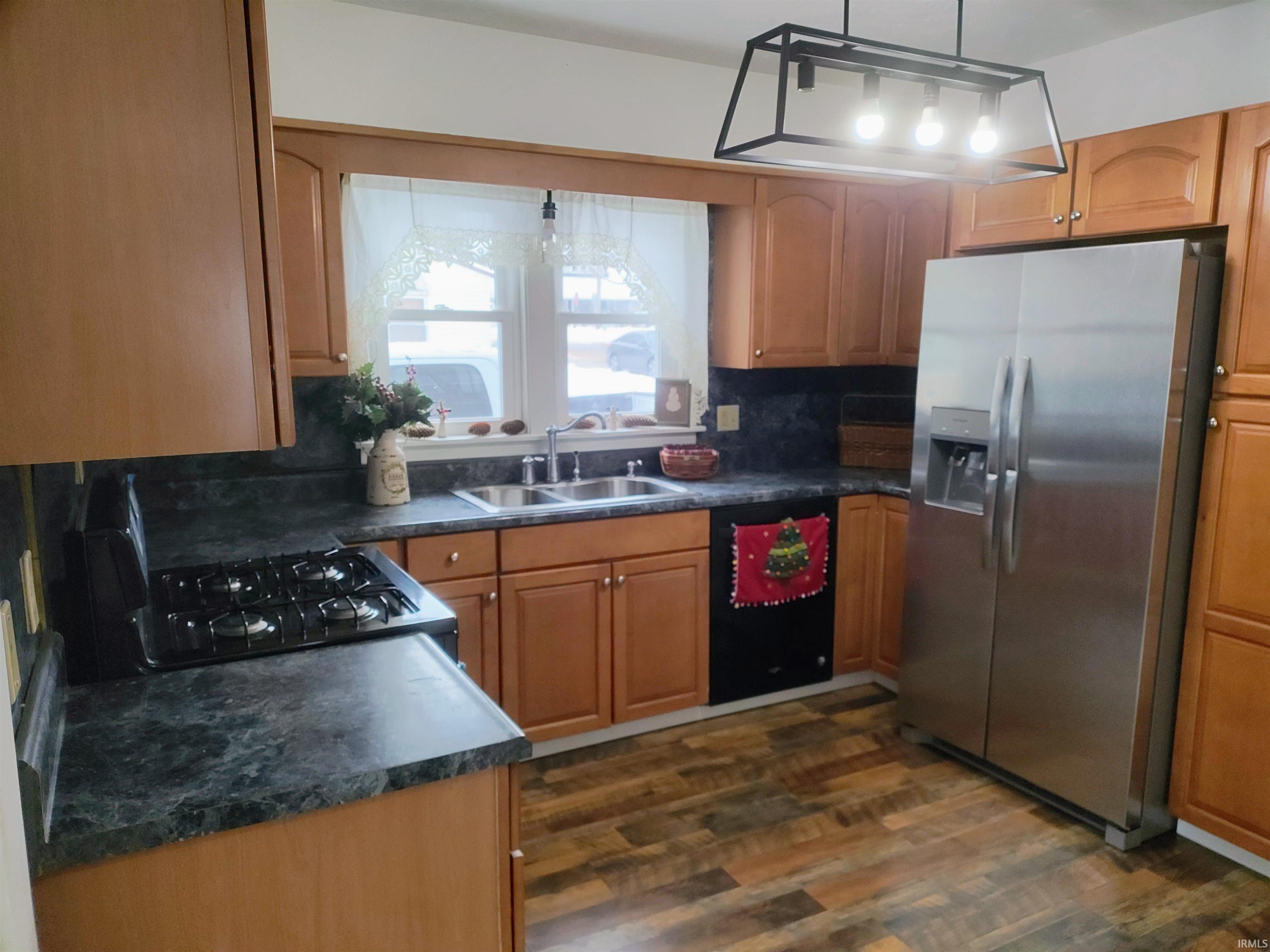 Kitchen featuring stainless steel fridge with ice dispenser, dark countertops, dishwasher, and gas range oven