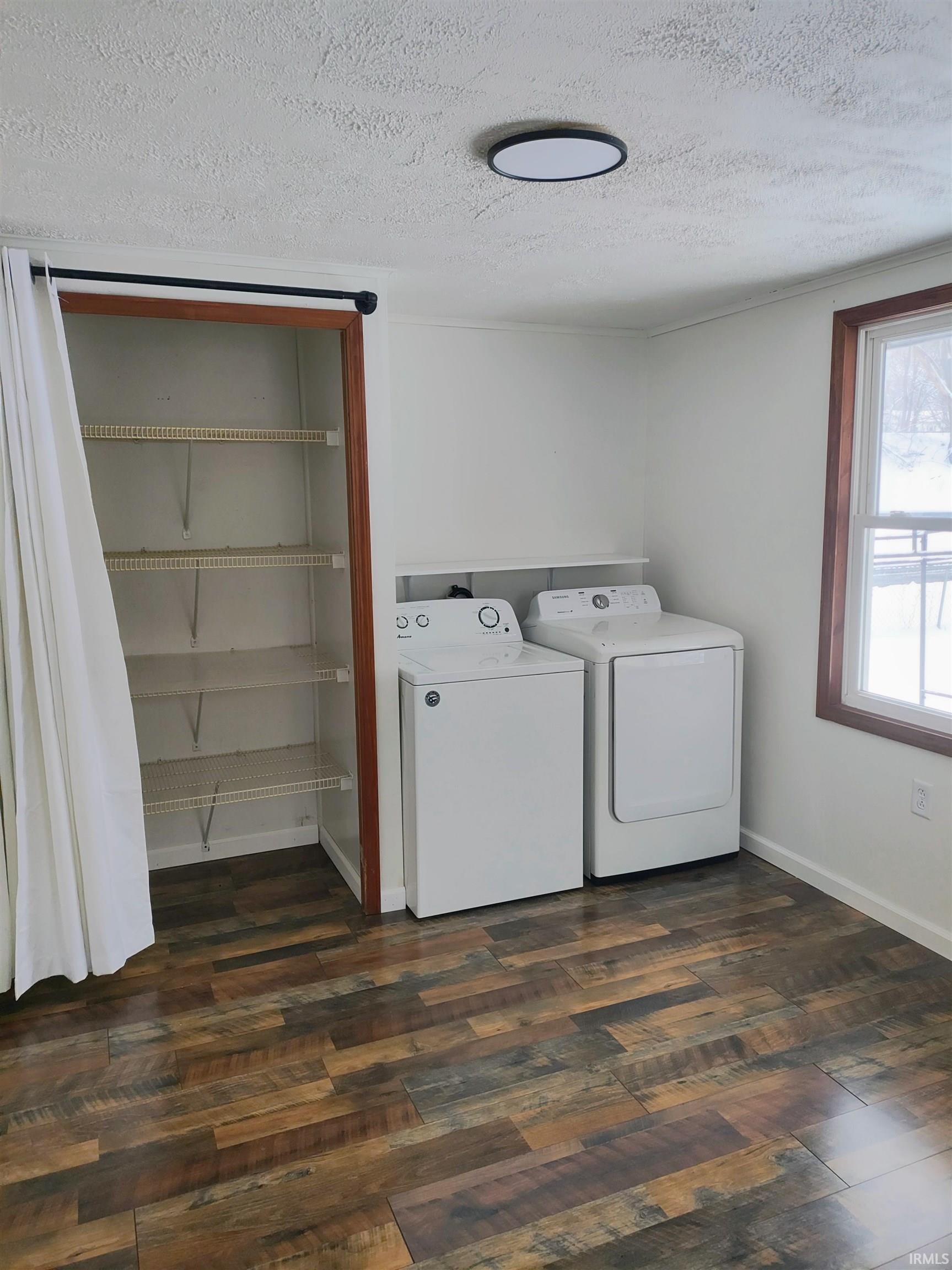 Laundry room featuring dark wood-style floors, a textured ceiling, and washing machine and dryer