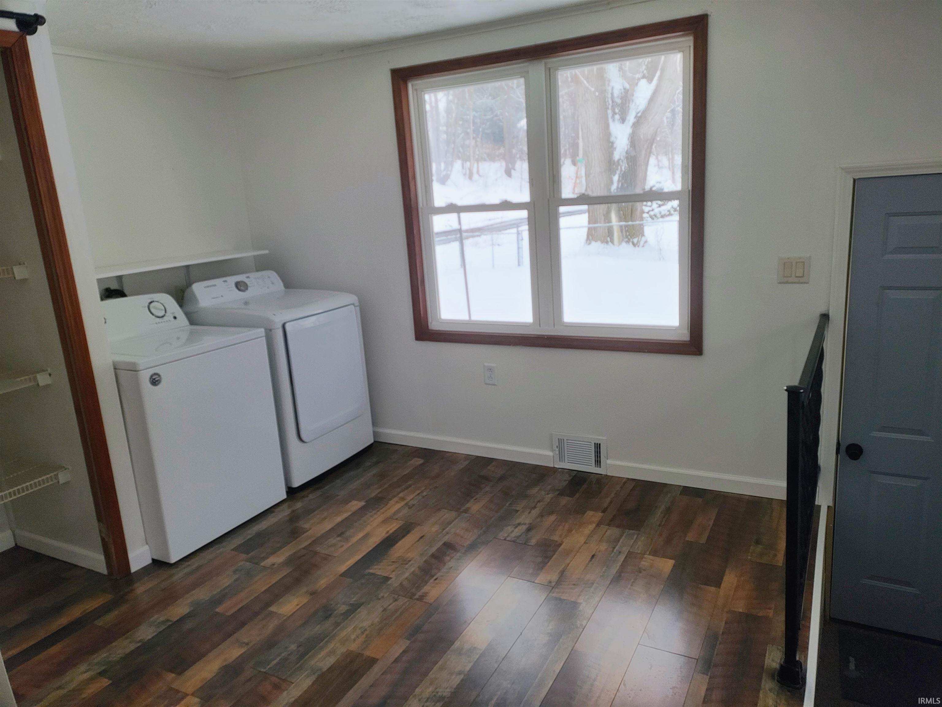Washroom with dark wood-style flooring and washer and dryer