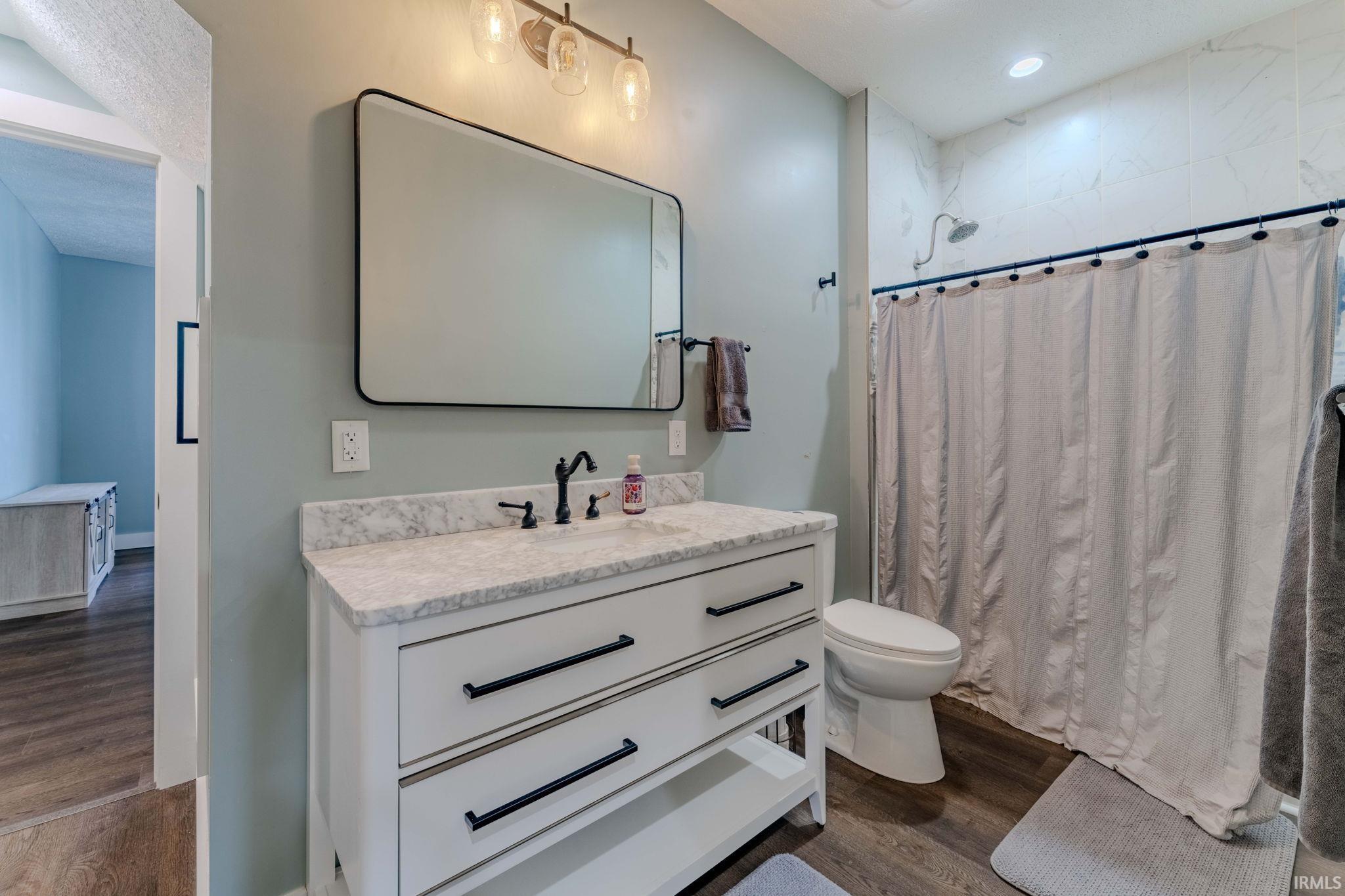 Bathroom featuring curtained shower, vanity, dark wood-style flooring, and recessed lighting