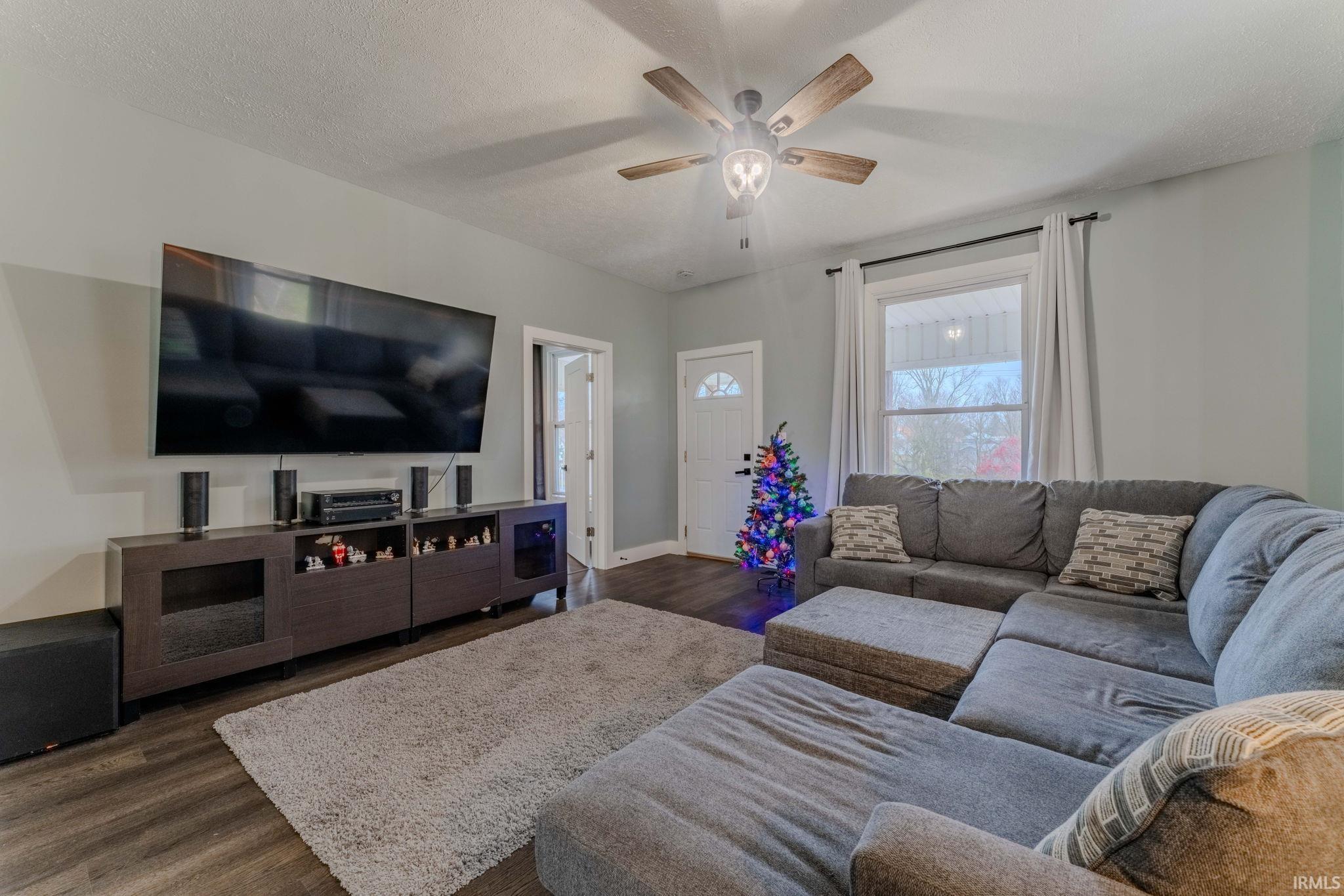 Living area with dark wood finished floors, a textured ceiling, and ceiling fan