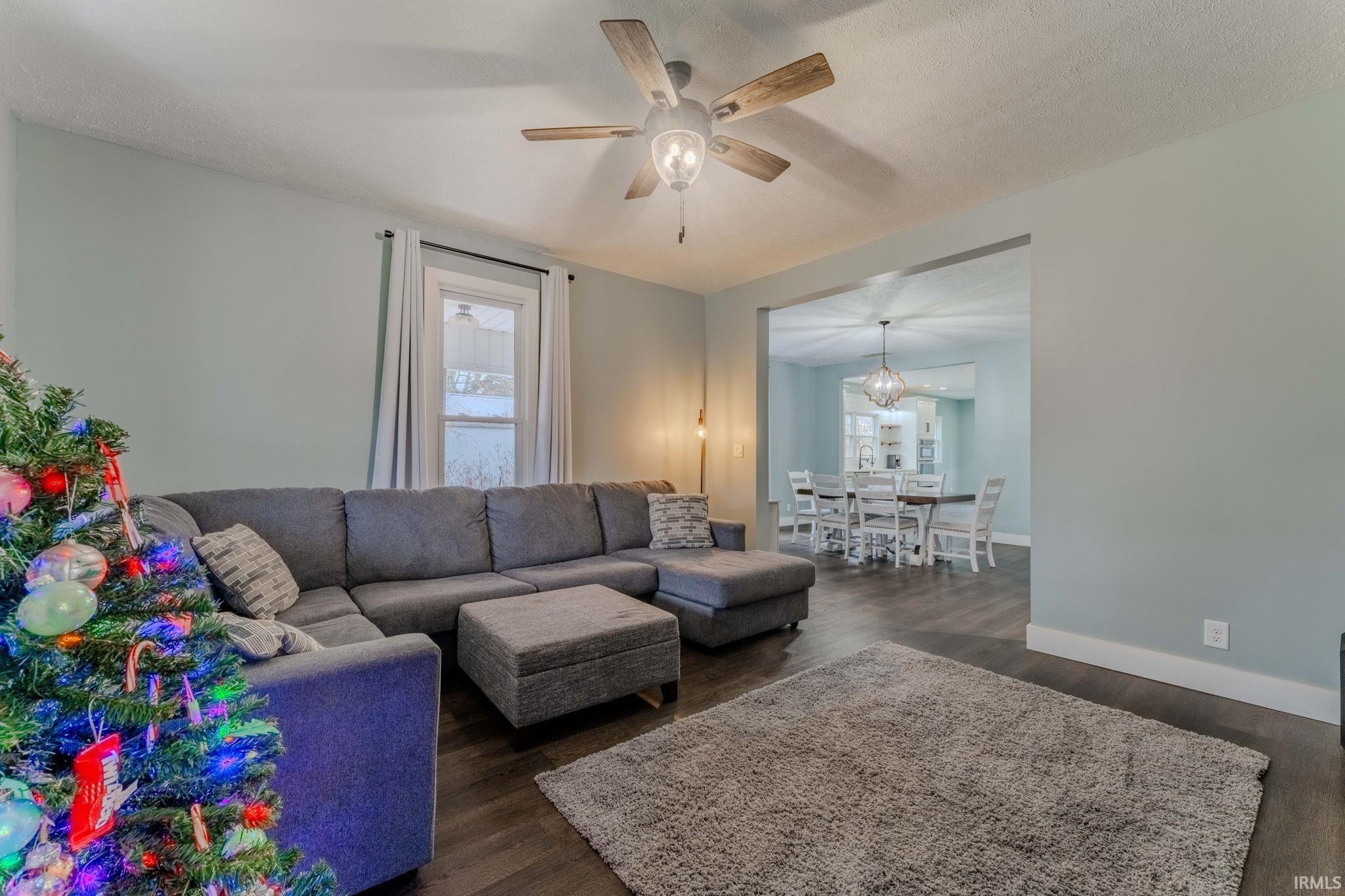Living area featuring dark wood finished floors, ceiling fan, and a textured ceiling