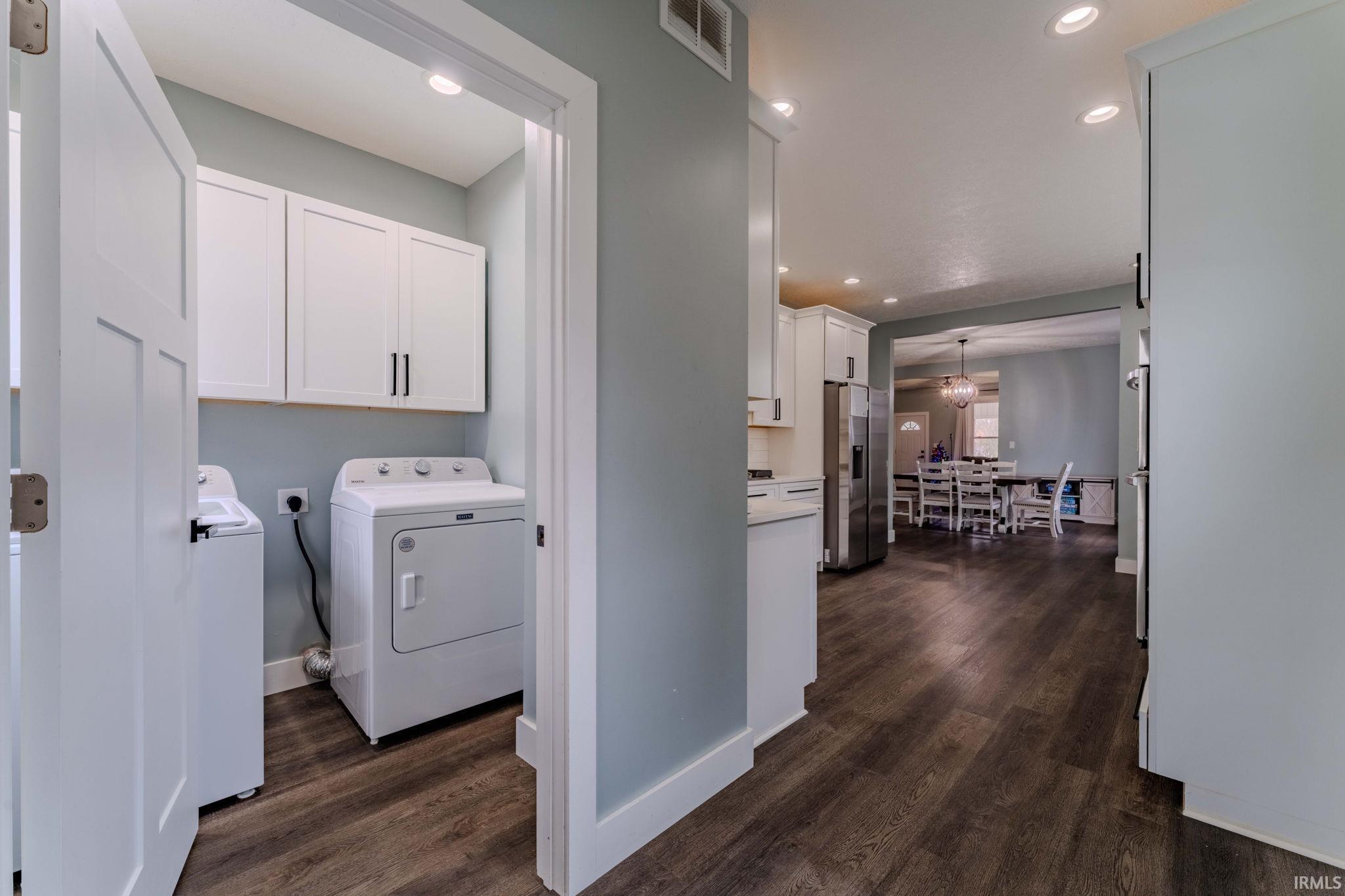 Laundry room with washer / dryer, recessed lighting, dark wood-type flooring, and cabinet space