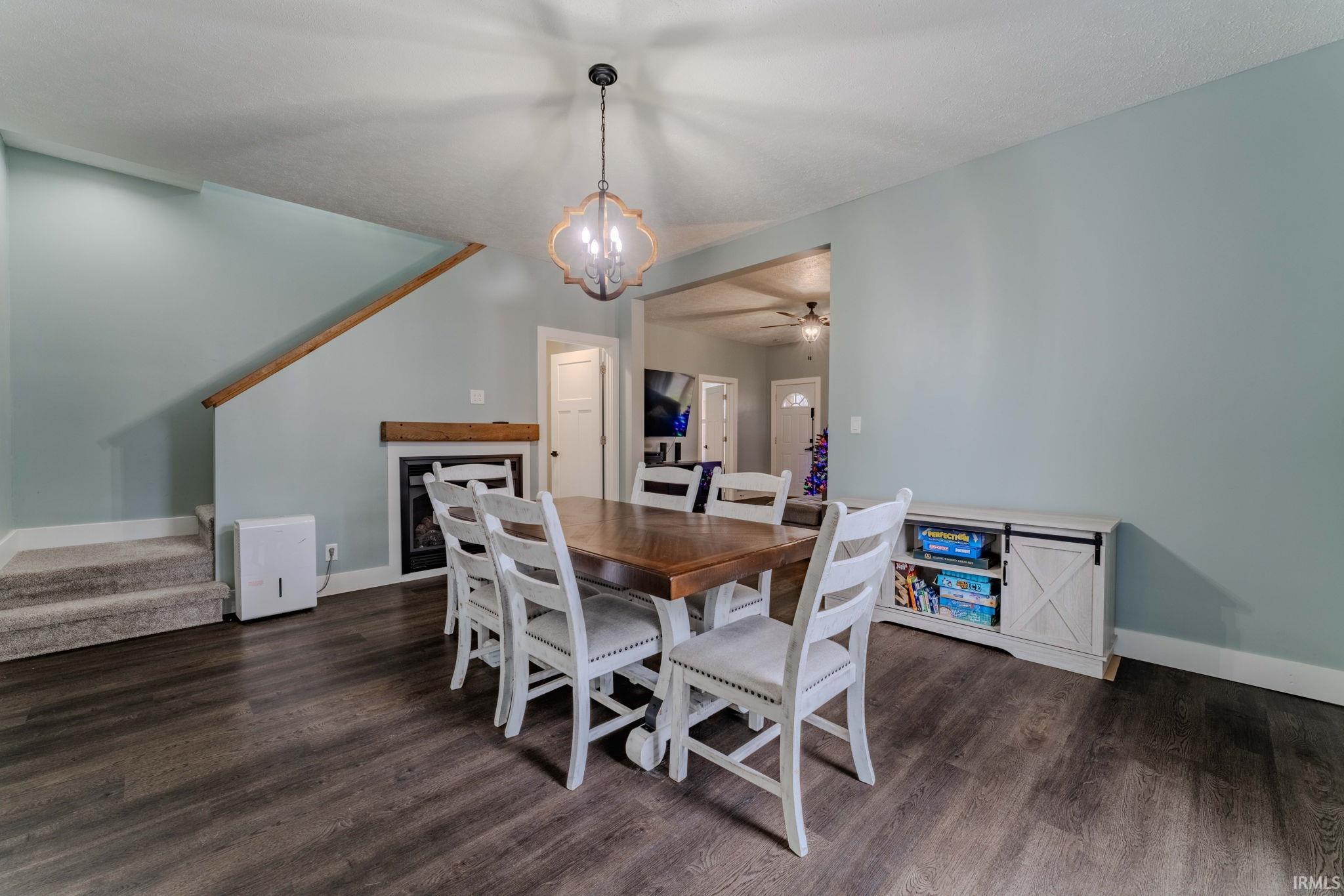 Dining area with stairs, a chandelier, and dark wood-style flooring