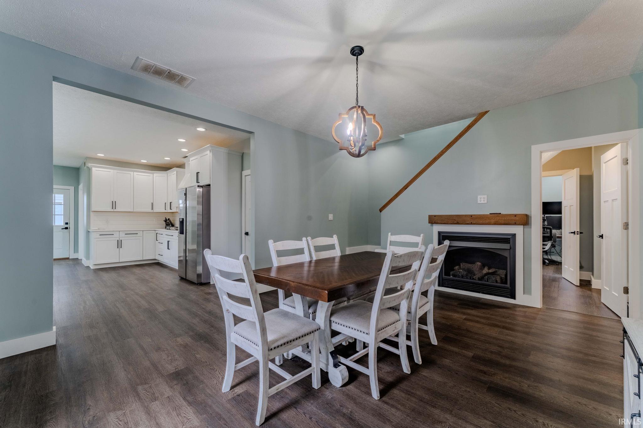 Dining room featuring a fireplace, dark wood-style floors, recessed lighting, and a chandelier