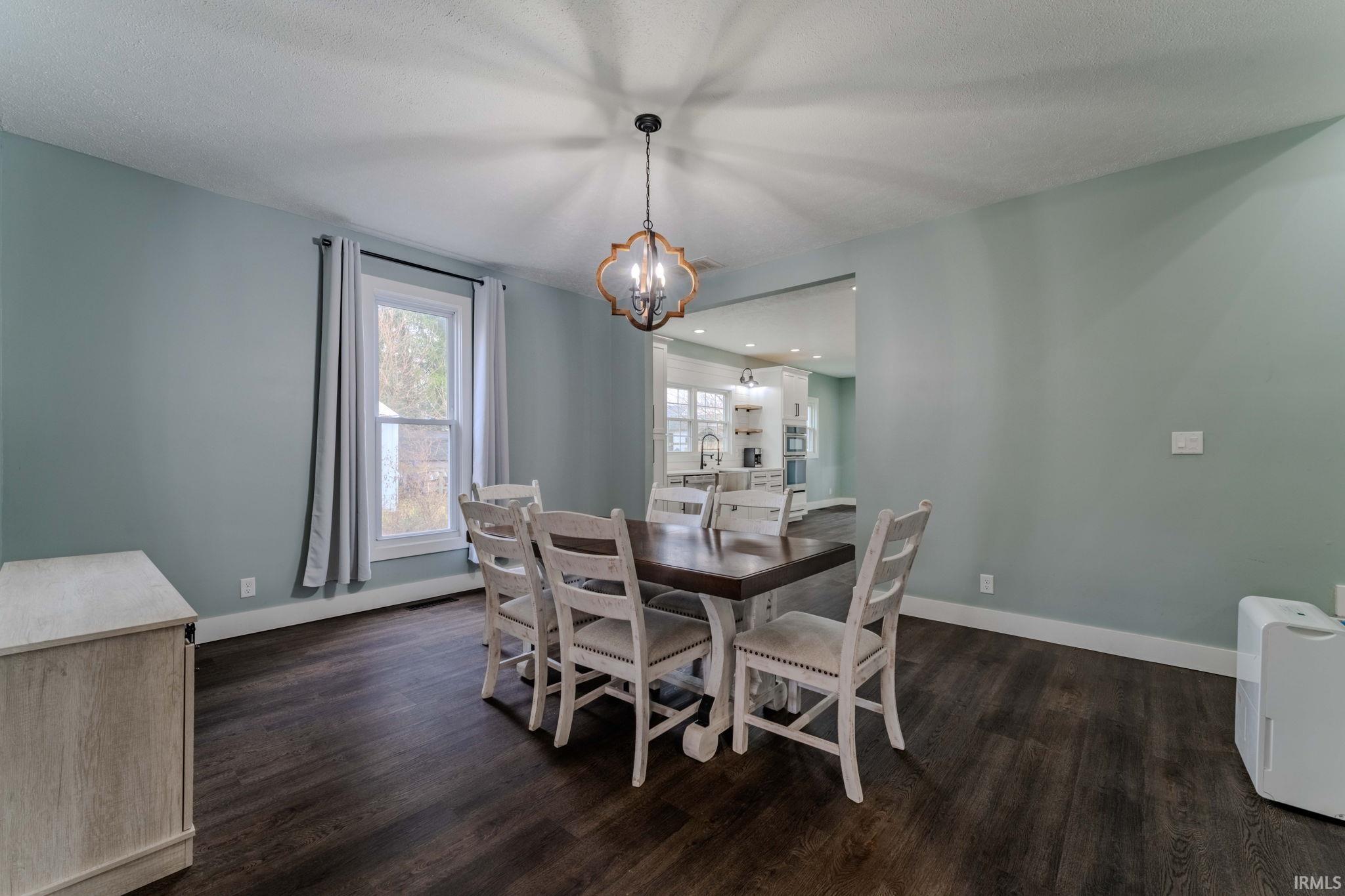 Dining room with dark wood-style flooring and a chandelier