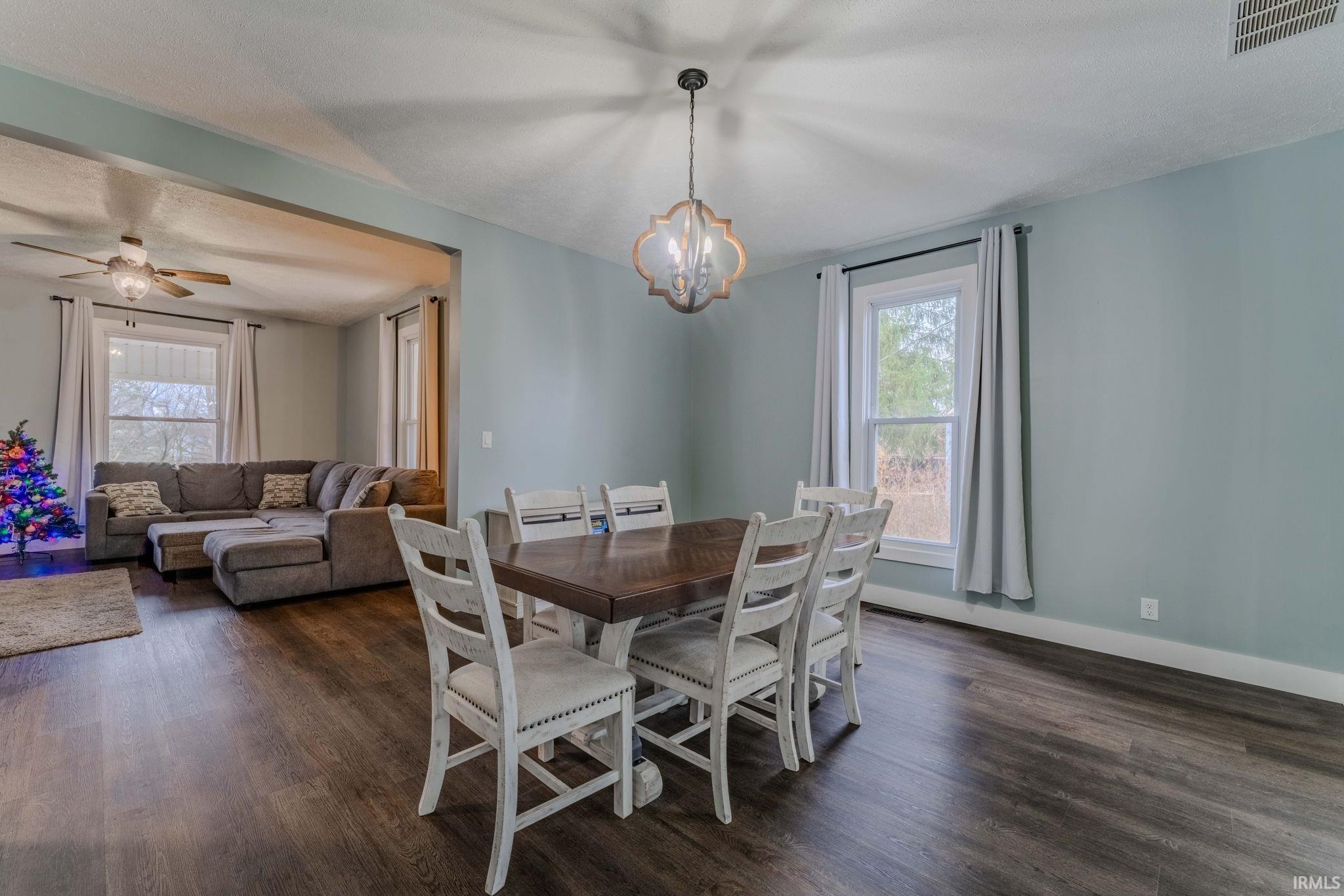 Dining room with dark wood-type flooring, a chandelier, and ceiling fan