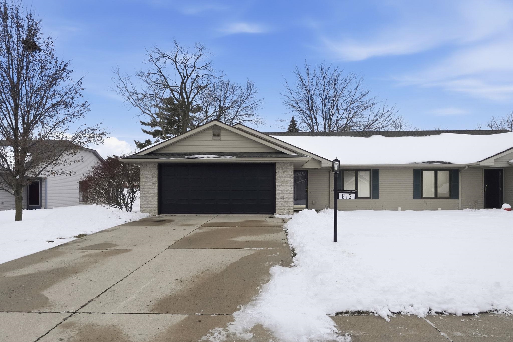 Single story home featuring driveway, brick siding, and a garage