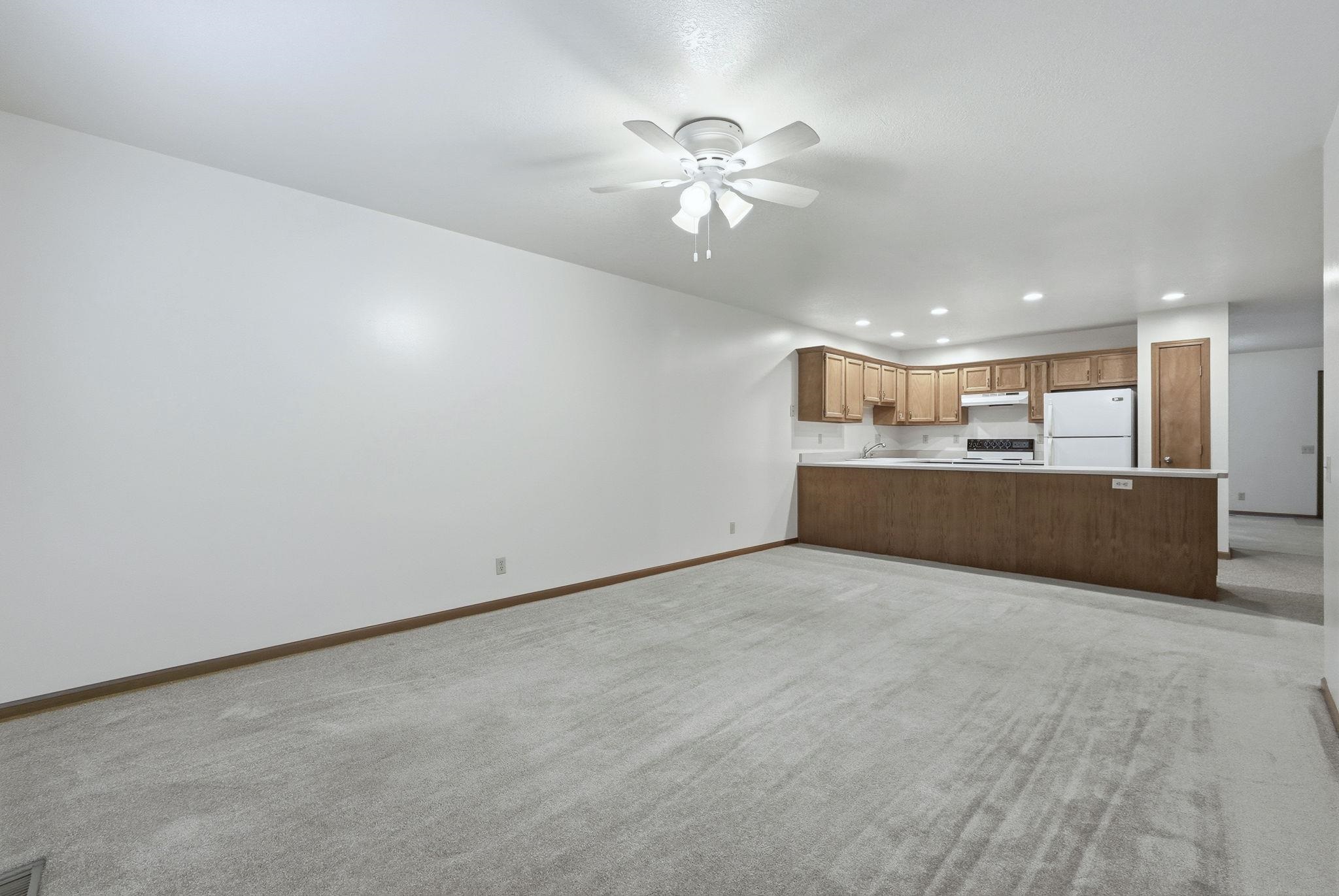 Unfurnished living room featuring recessed lighting, light colored carpet, and a ceiling fan