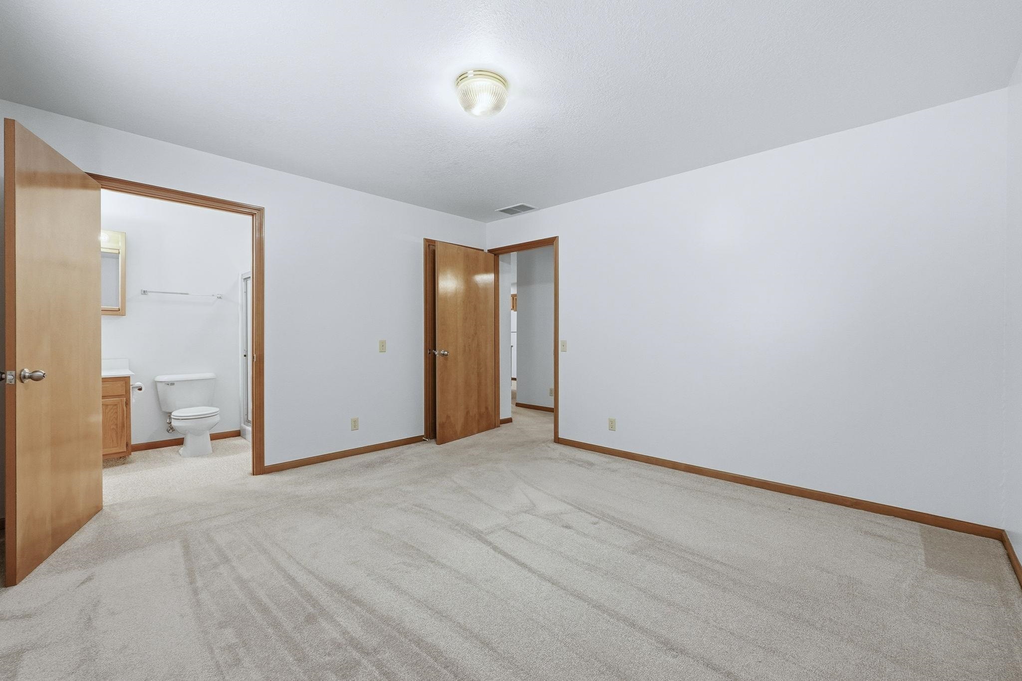 Unfurnished bedroom with light colored carpet and ensuite bathroom