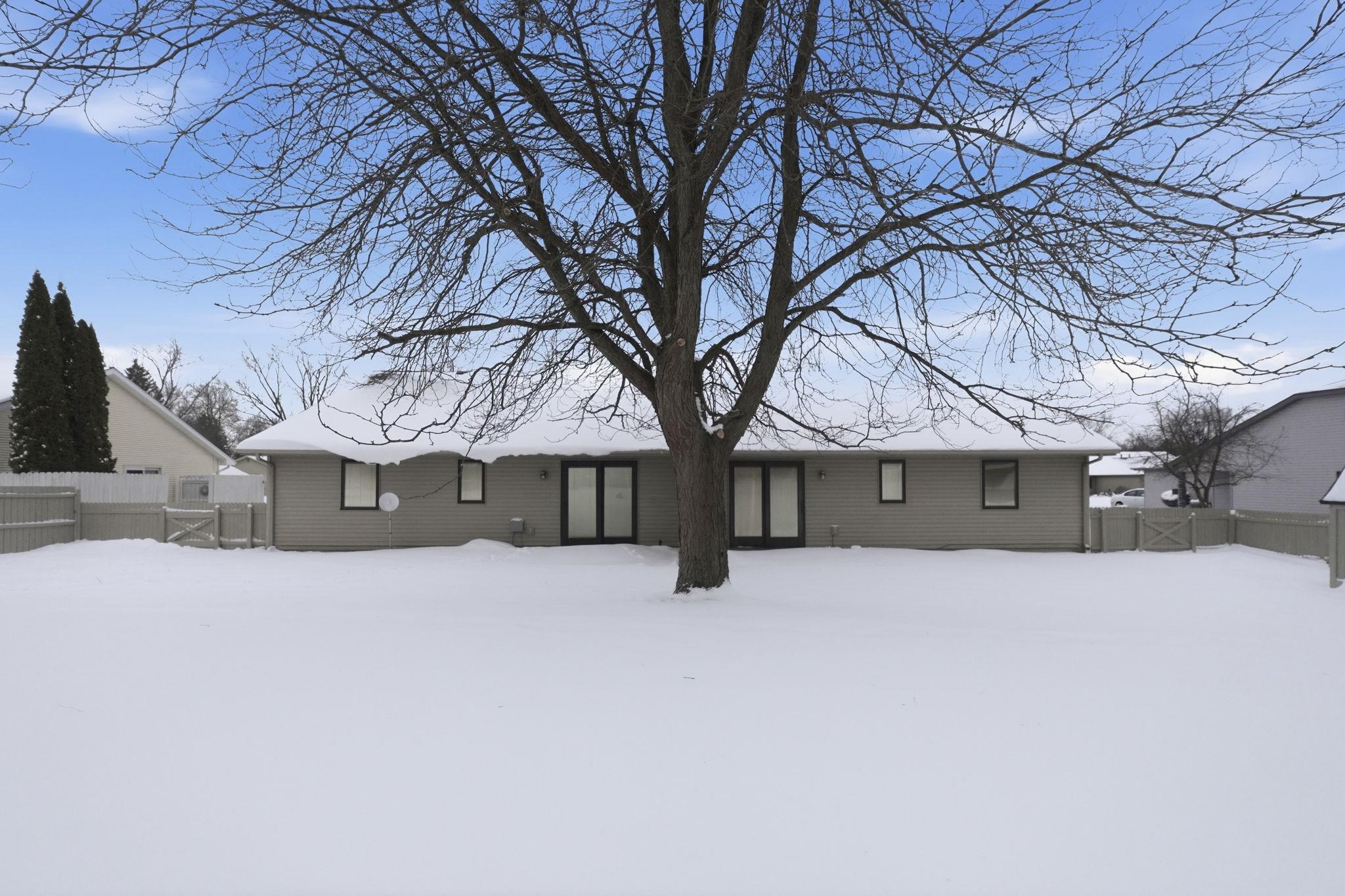 Snow covered rear of property with a fenced backyard and a gate
