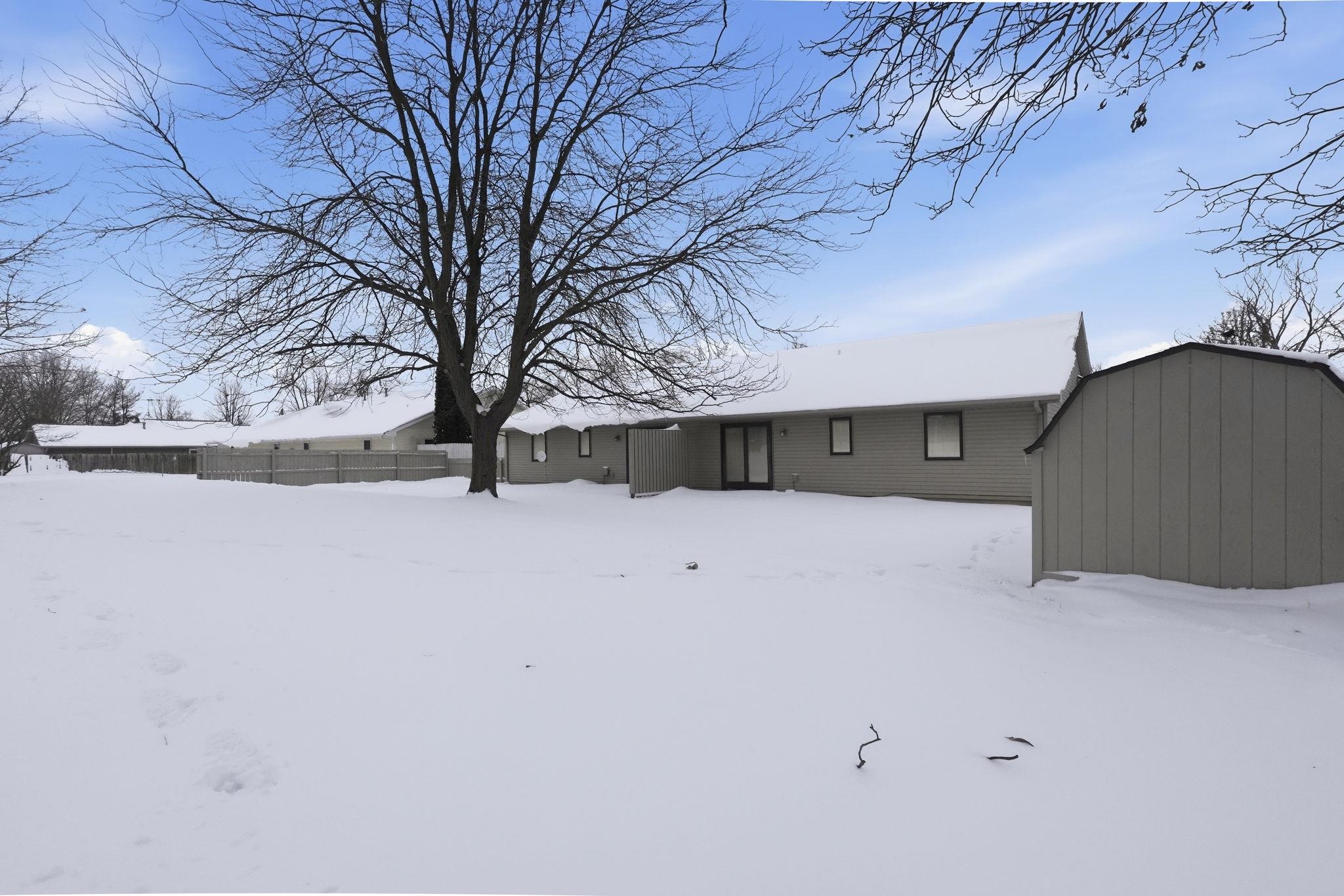 Snow covered property featuring a storage shed