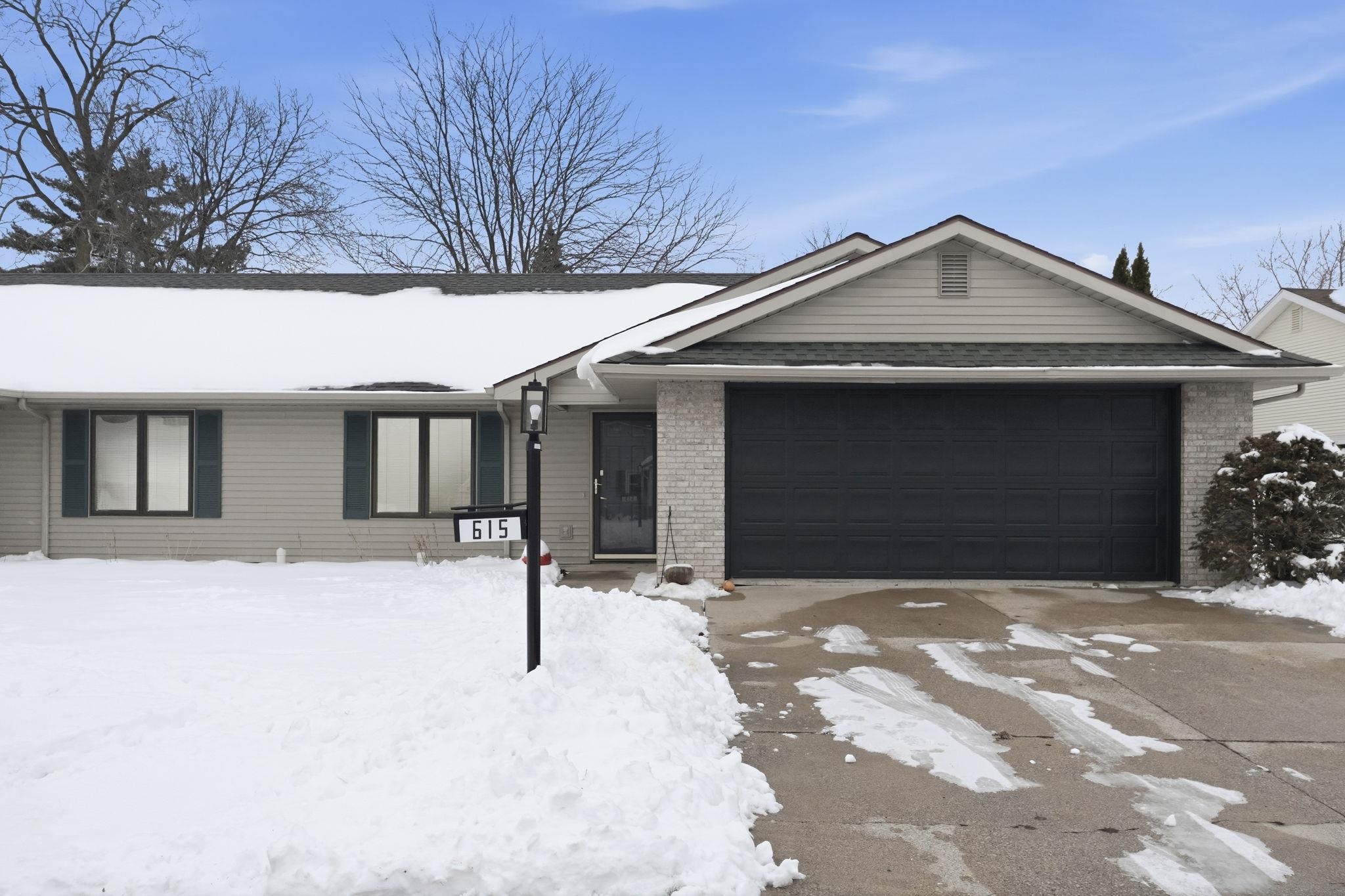 Single story home with driveway, brick siding, and an attached garage