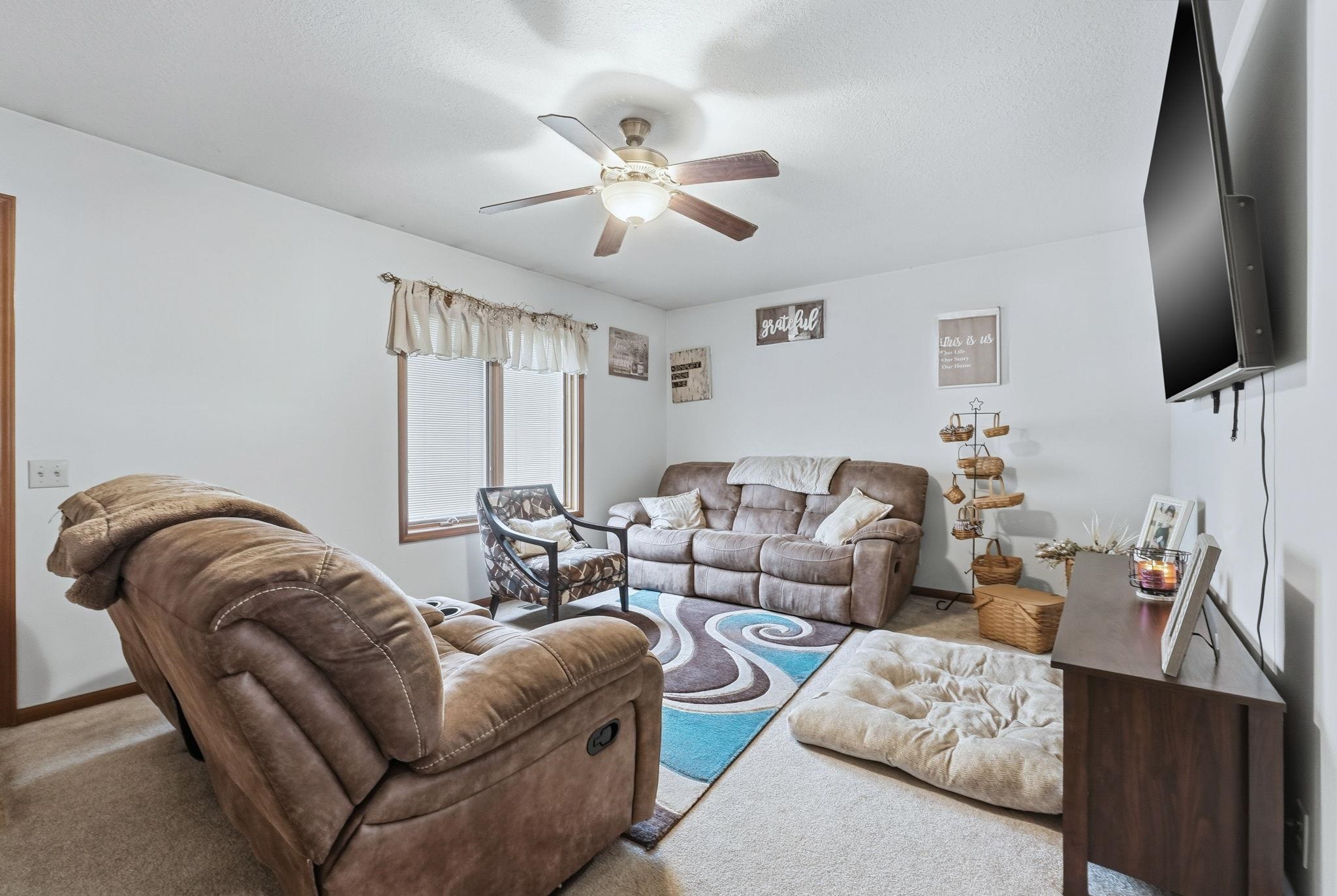 Living room featuring a ceiling fan and carpet floors
