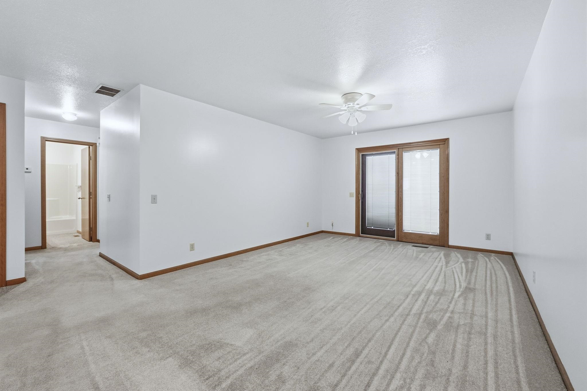 Empty room featuring light colored carpet and a ceiling fan