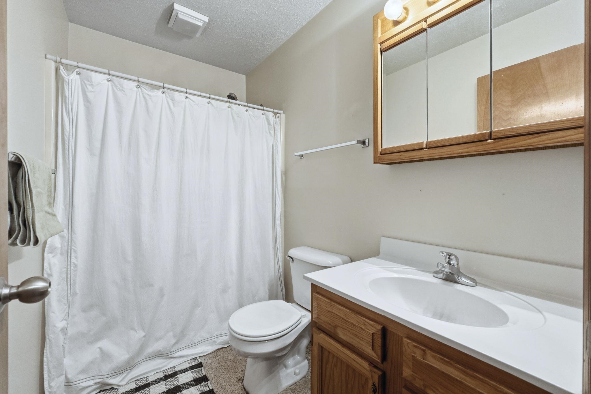 Full bath featuring a shower with curtain, vanity, and a textured ceiling