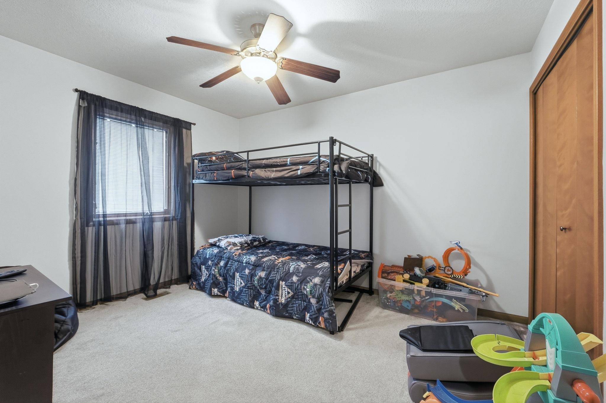 Bedroom featuring light carpet, a ceiling fan, and a closet