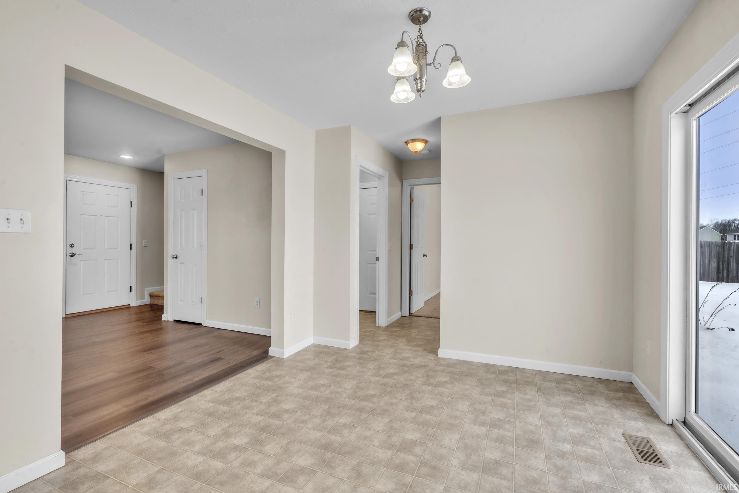 Unfurnished room featuring baseboards and a chandelier