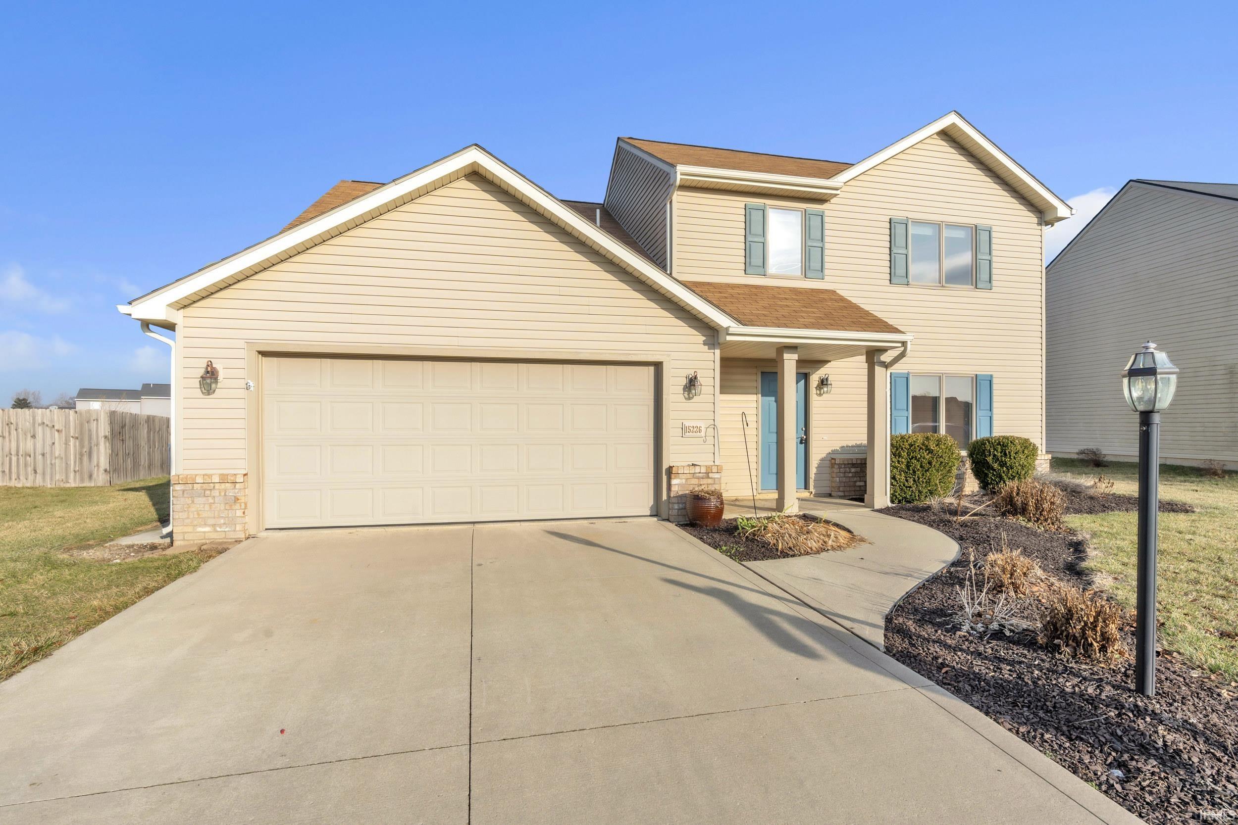 Traditional-style home featuring concrete driveway, a garage, and roof with shingles
