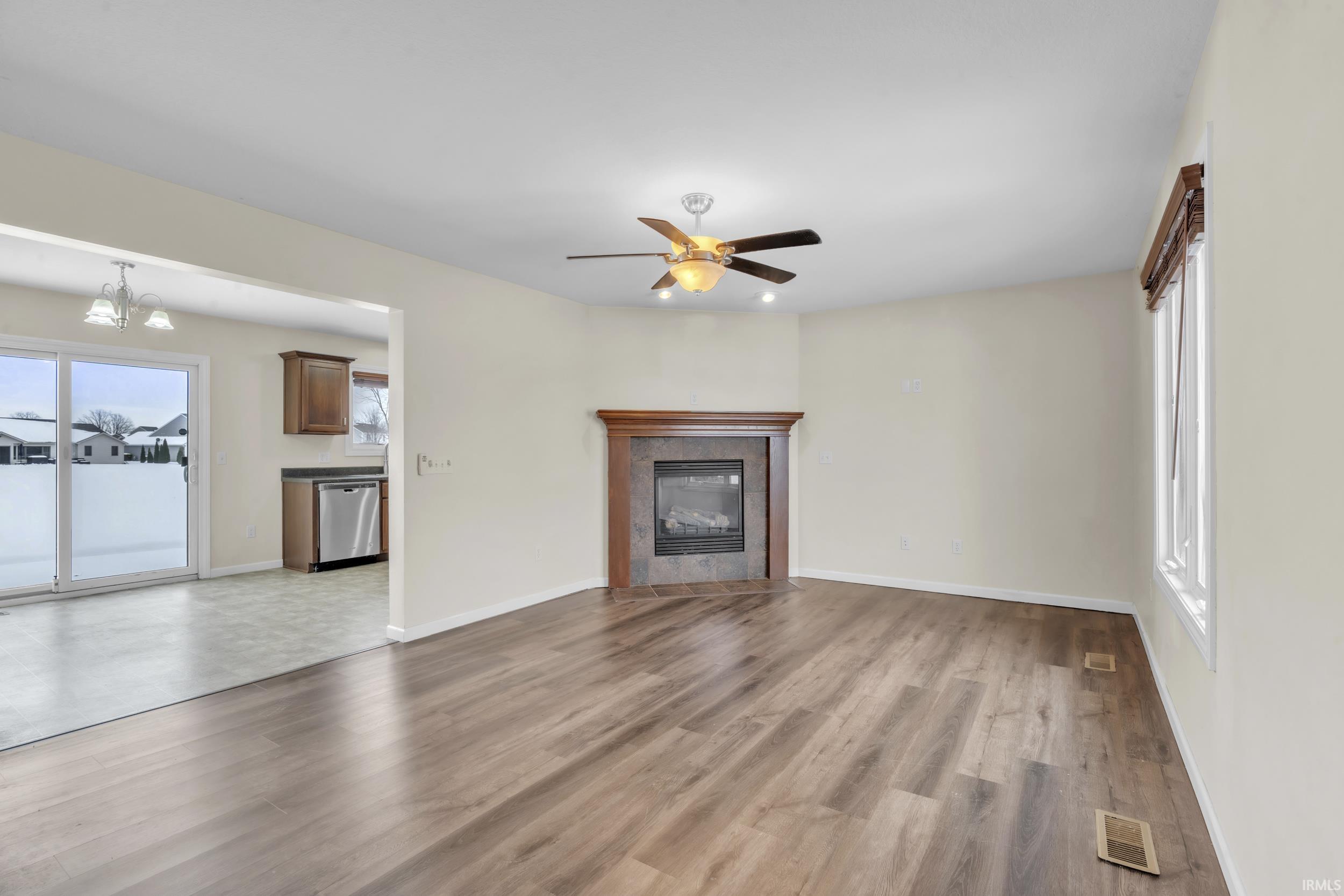 Unfurnished living room featuring light wood finished floors, a fireplace, ceiling fan, and a chandelier