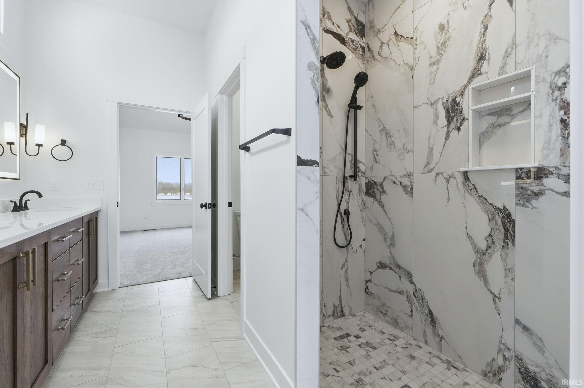 Full bathroom with vanity, a marble finish shower, and light marble finish flooring