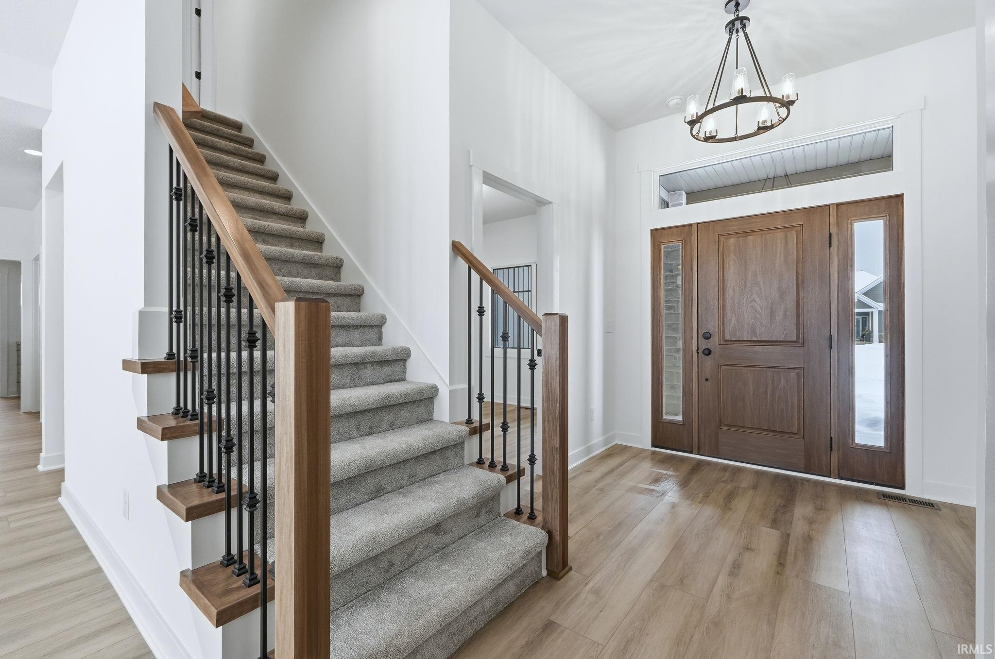 Foyer entrance featuring light wood-style floors, stairs, and a chandelier