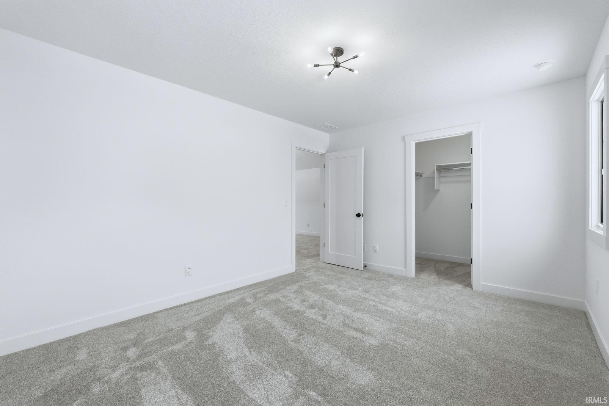 Unfurnished bedroom with a walk in closet and carpet floors