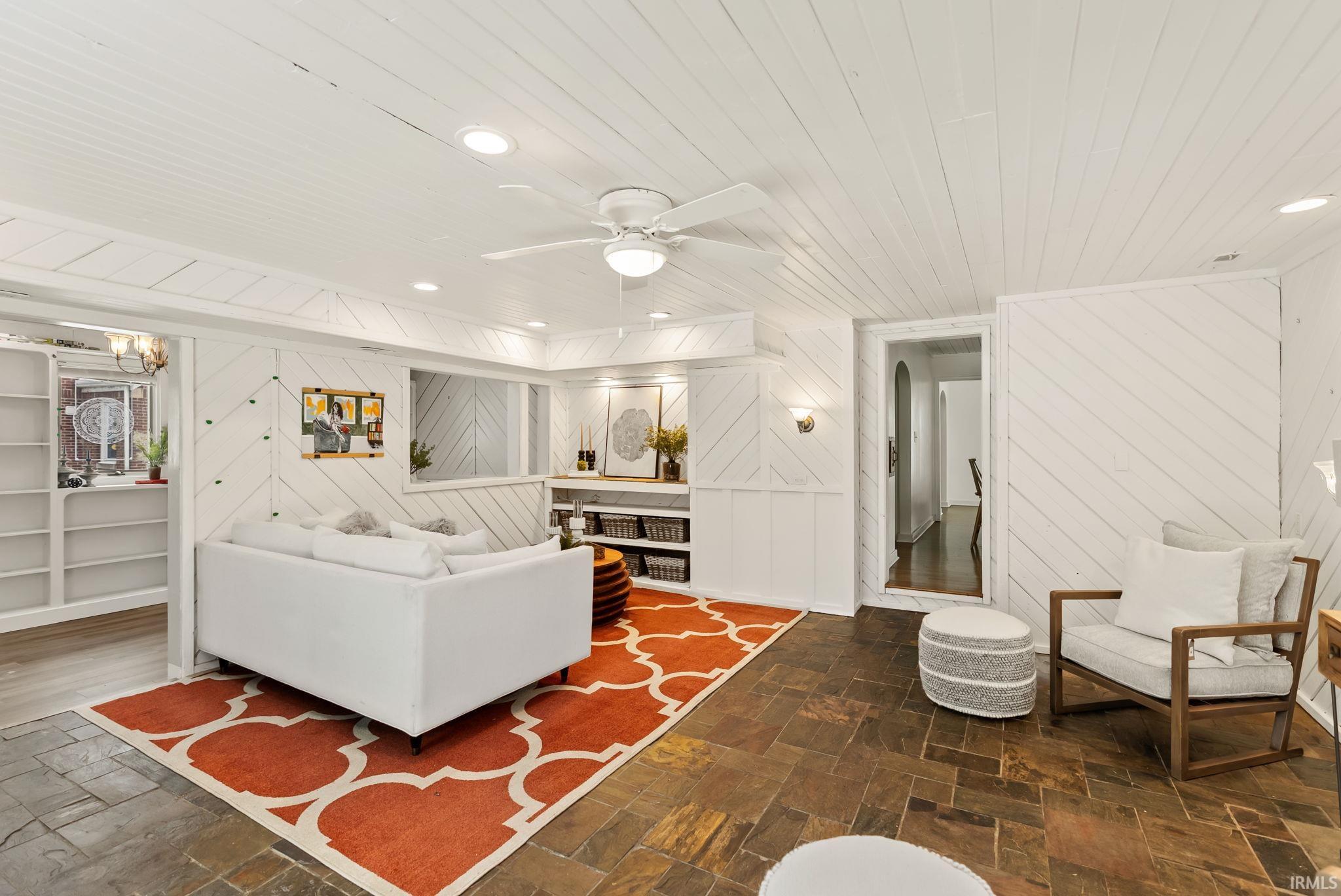 Living room featuring stone tile flooring, wooden ceiling, wood walls, recessed lighting, and ceiling fan