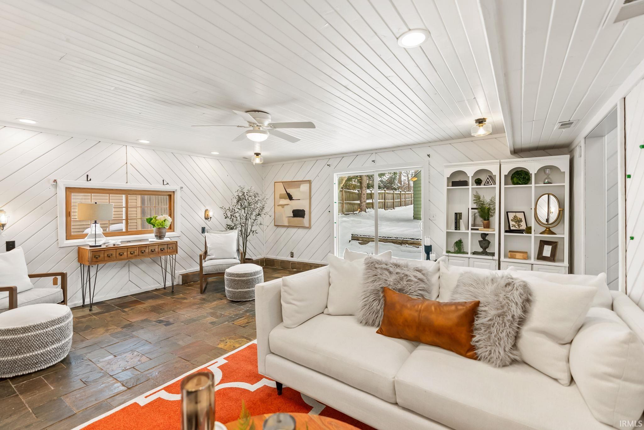 Living area with wood ceiling, stone tile floors, wooden walls, recessed lighting, and ceiling fan