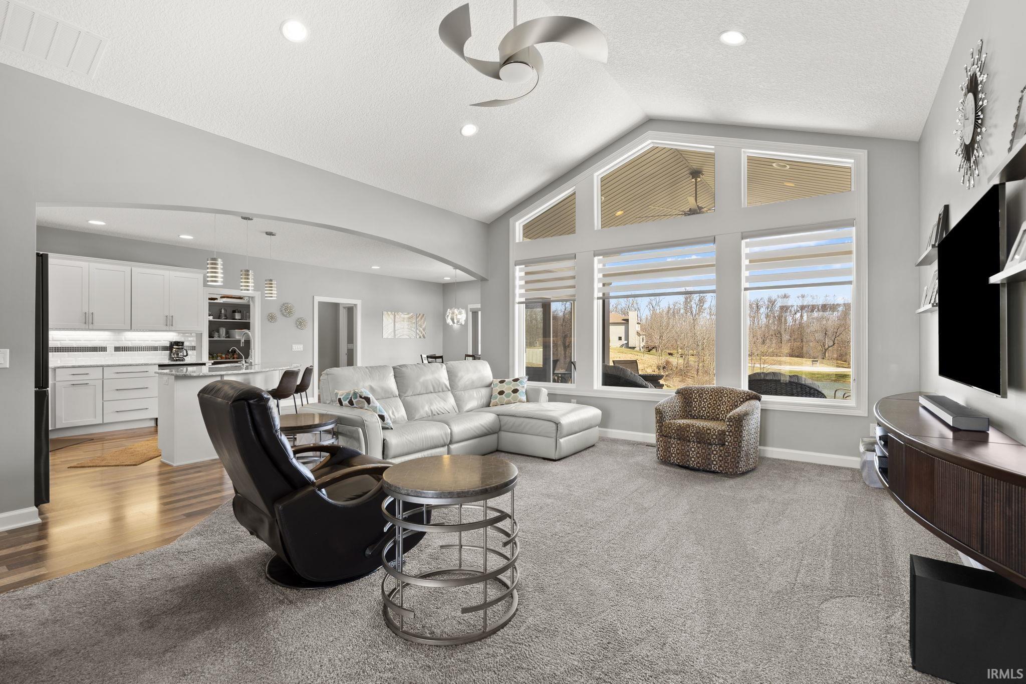 Living room with vaulted ceiling, recessed lighting, light carpet, ceiling fan, and arched walkways