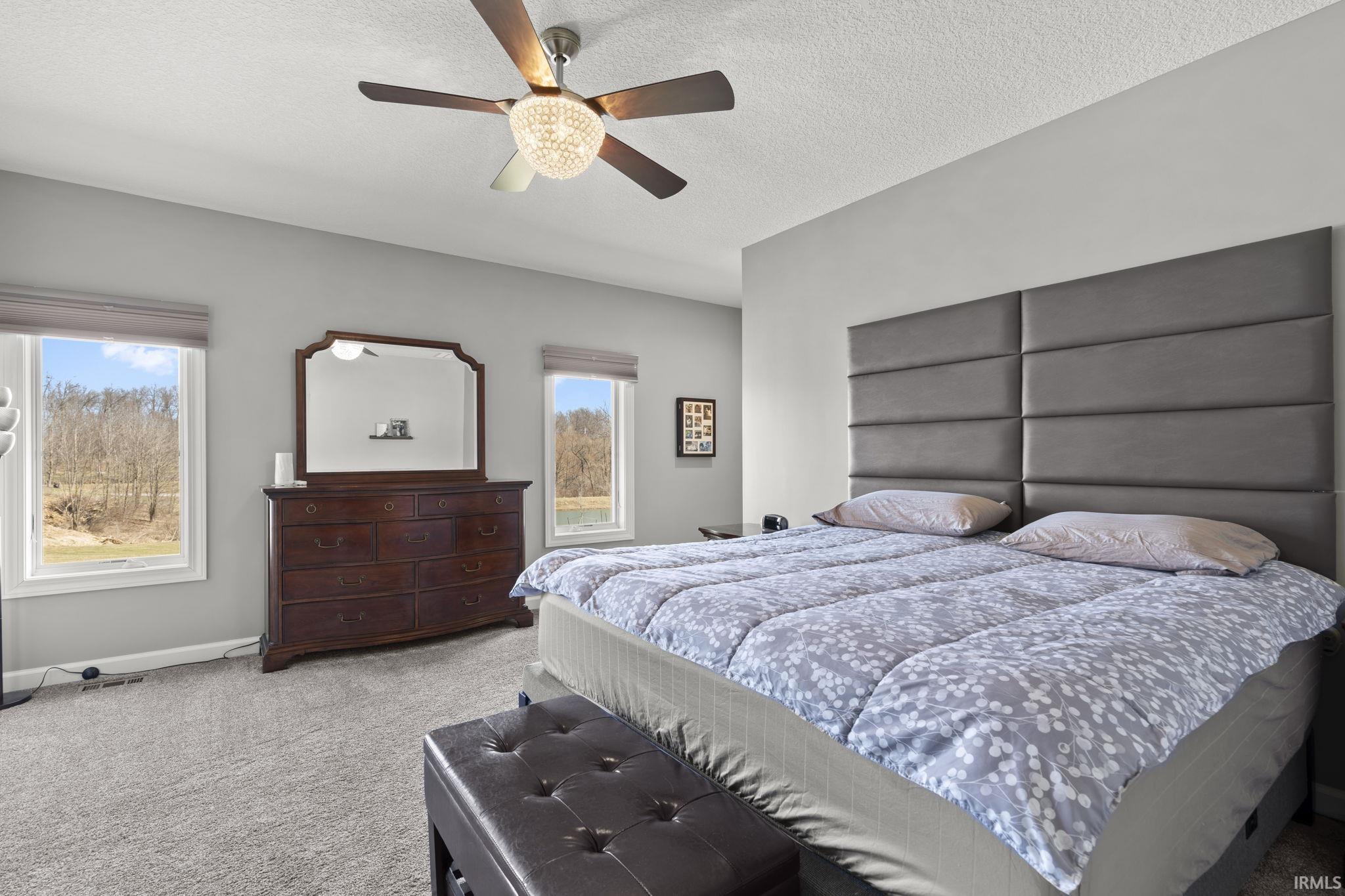 Carpeted bedroom featuring a textured ceiling and a ceiling fan