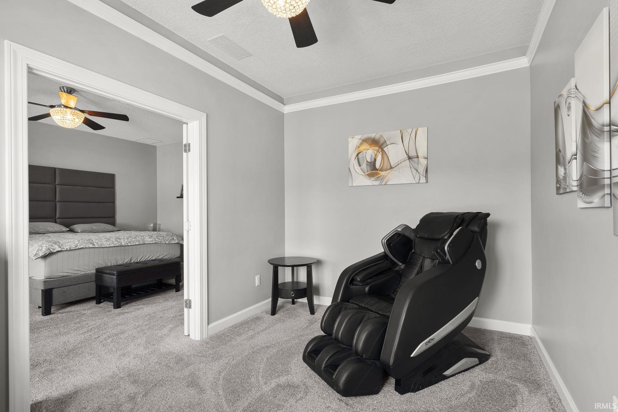 Living area featuring carpet flooring, a textured ceiling, ceiling fan, and crown molding