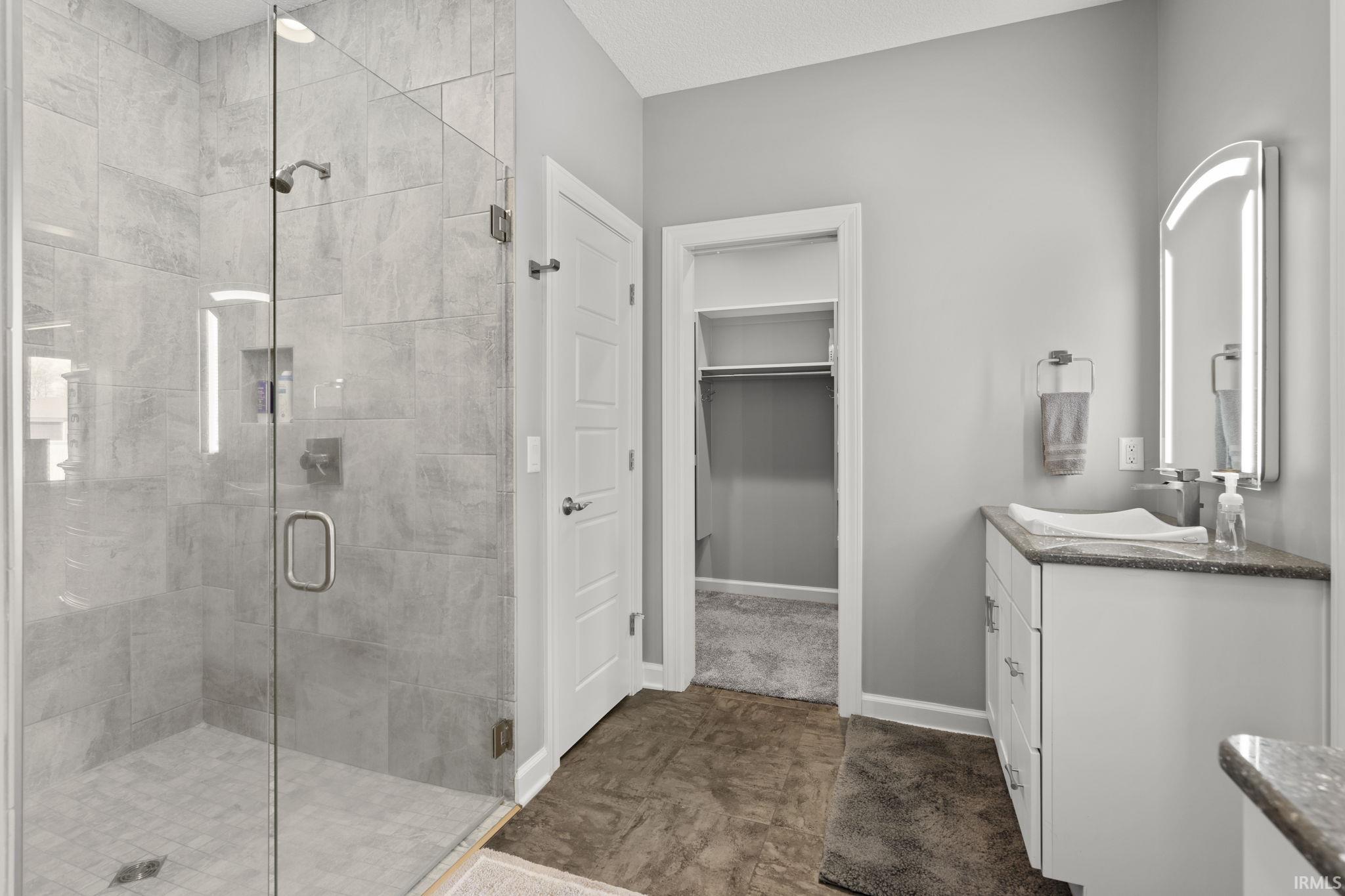 Full bathroom with vanity, a spacious closet, and a stall shower