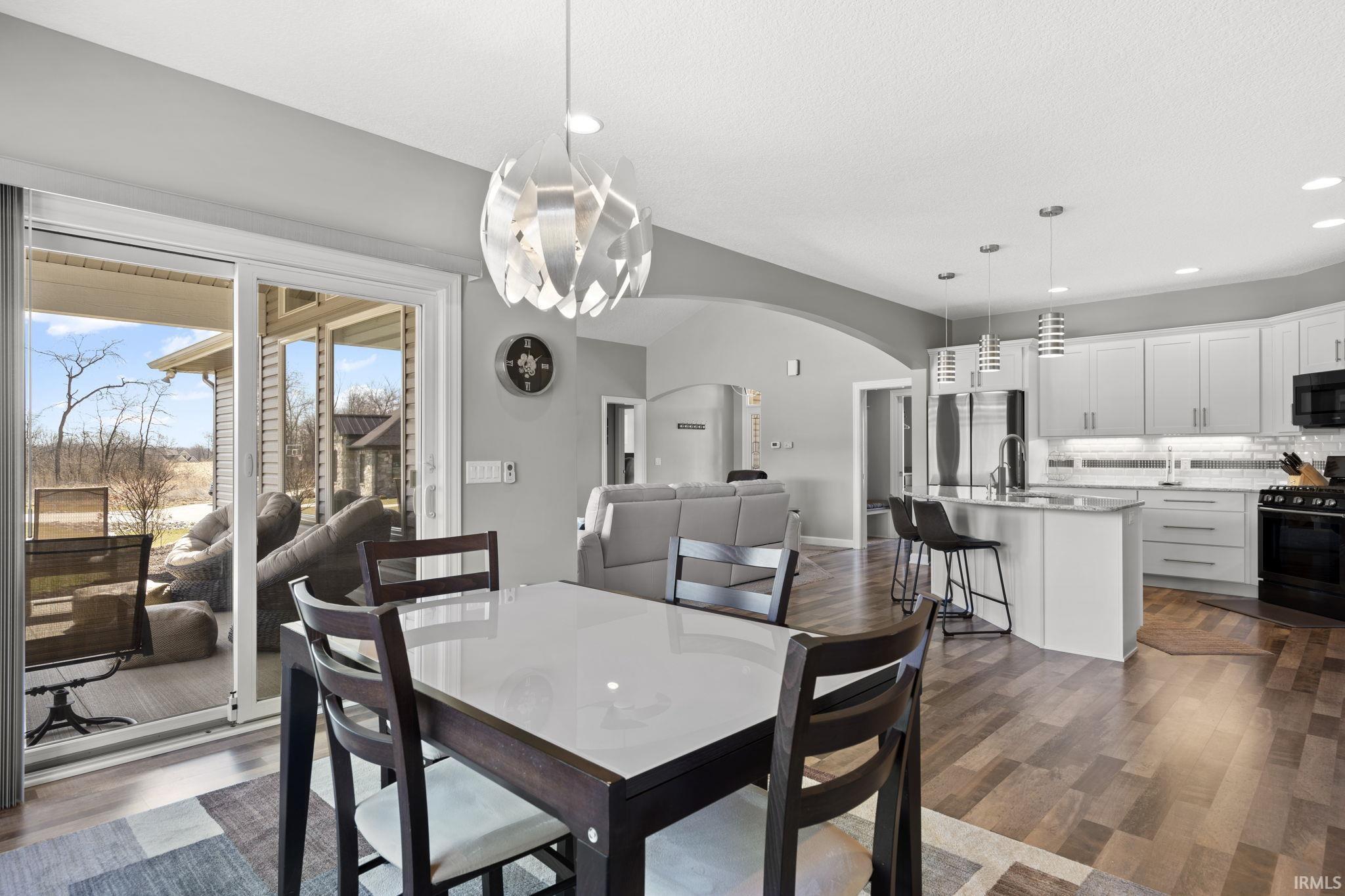 Dining space featuring dark wood finished floors, arched walkways, and recessed lighting