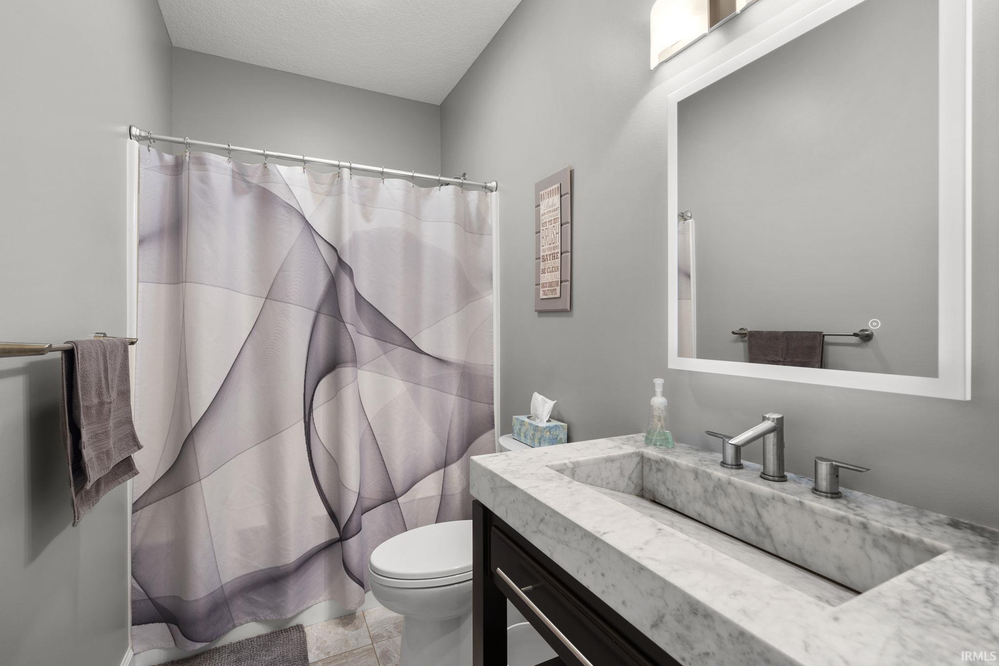 Full bath with a shower with shower curtain, vanity, and a textured ceiling