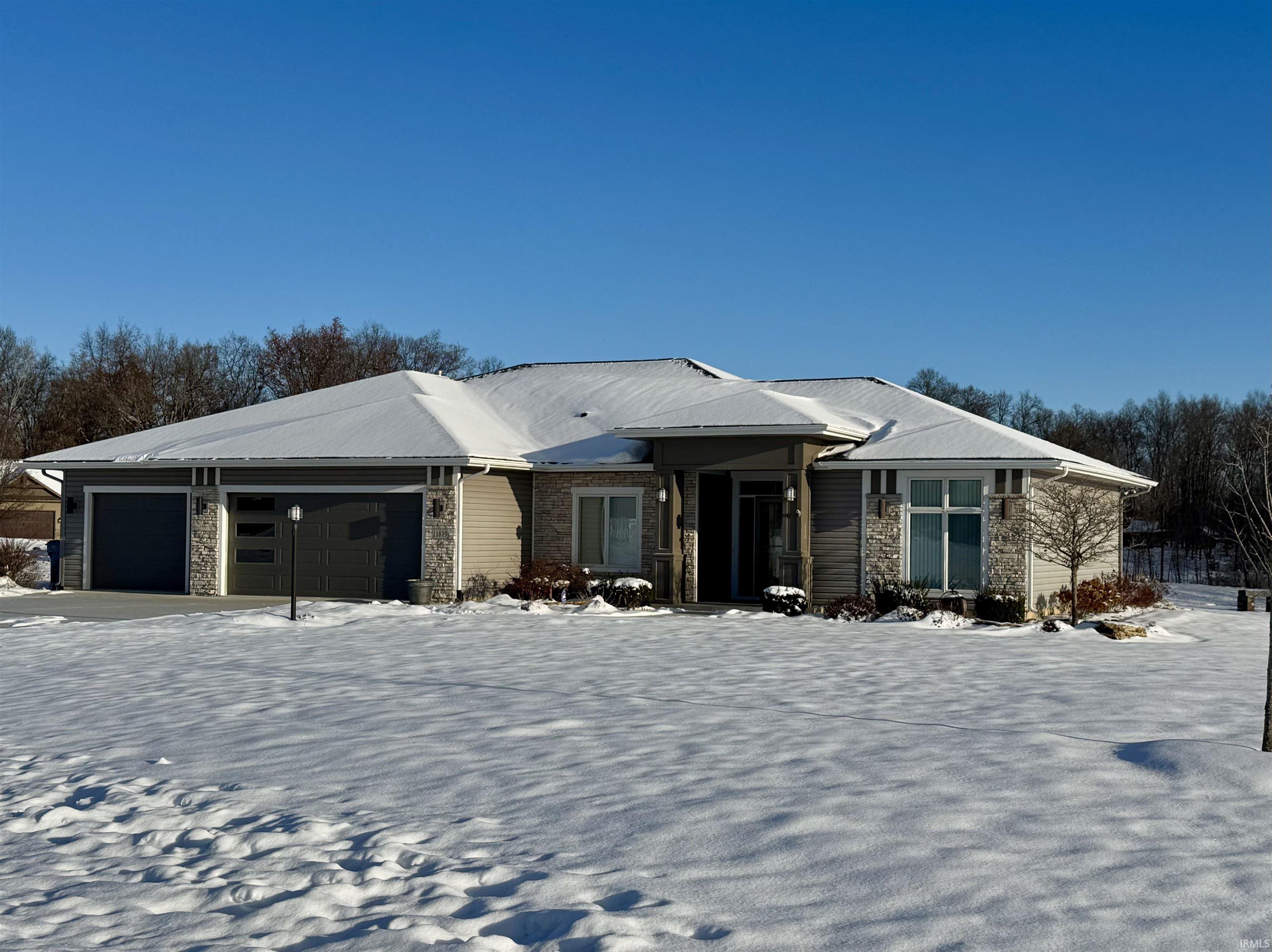 Ranch-style home featuring a garage, stone siding, and driveway