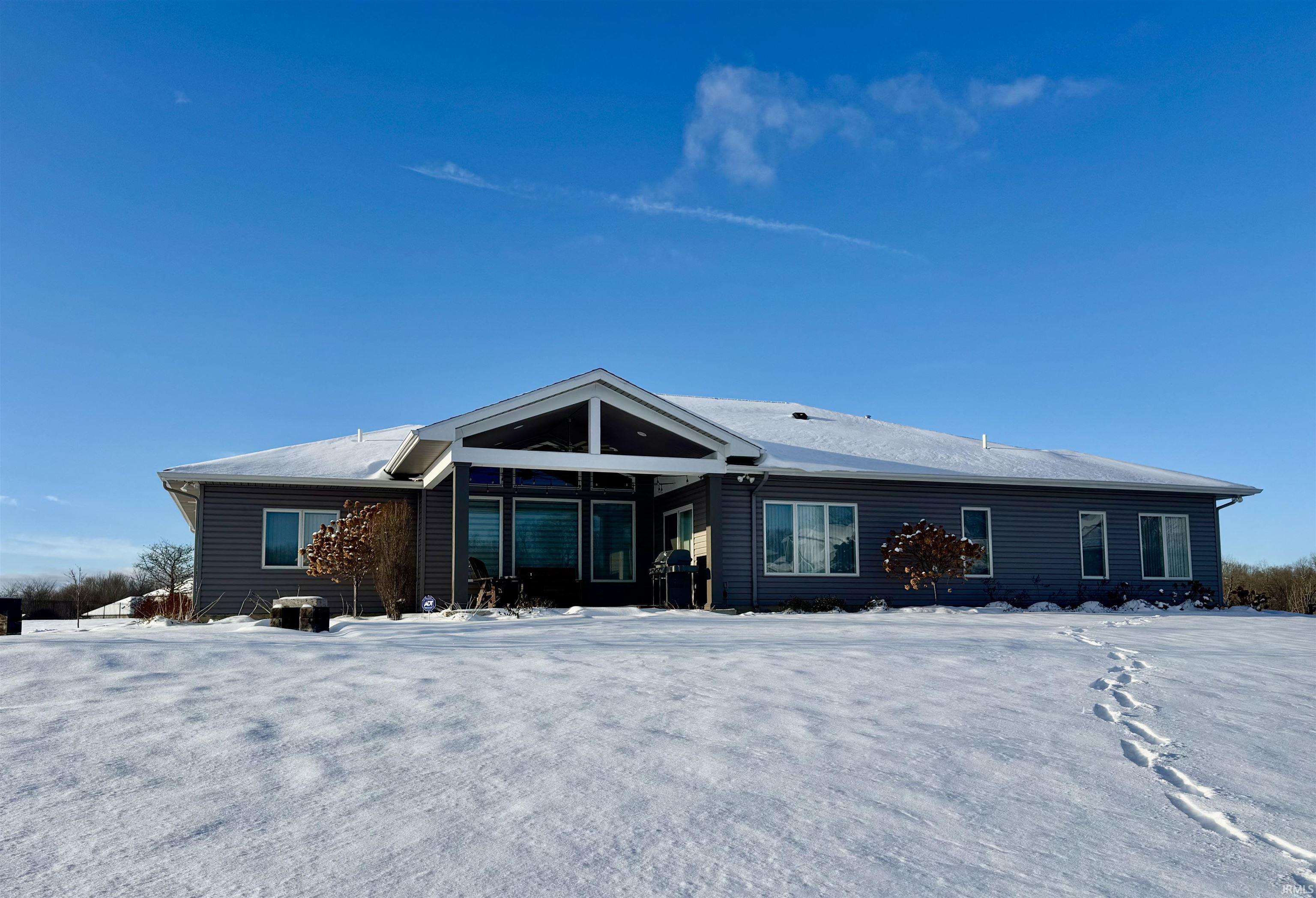 Snow covered back of property featuring a patio