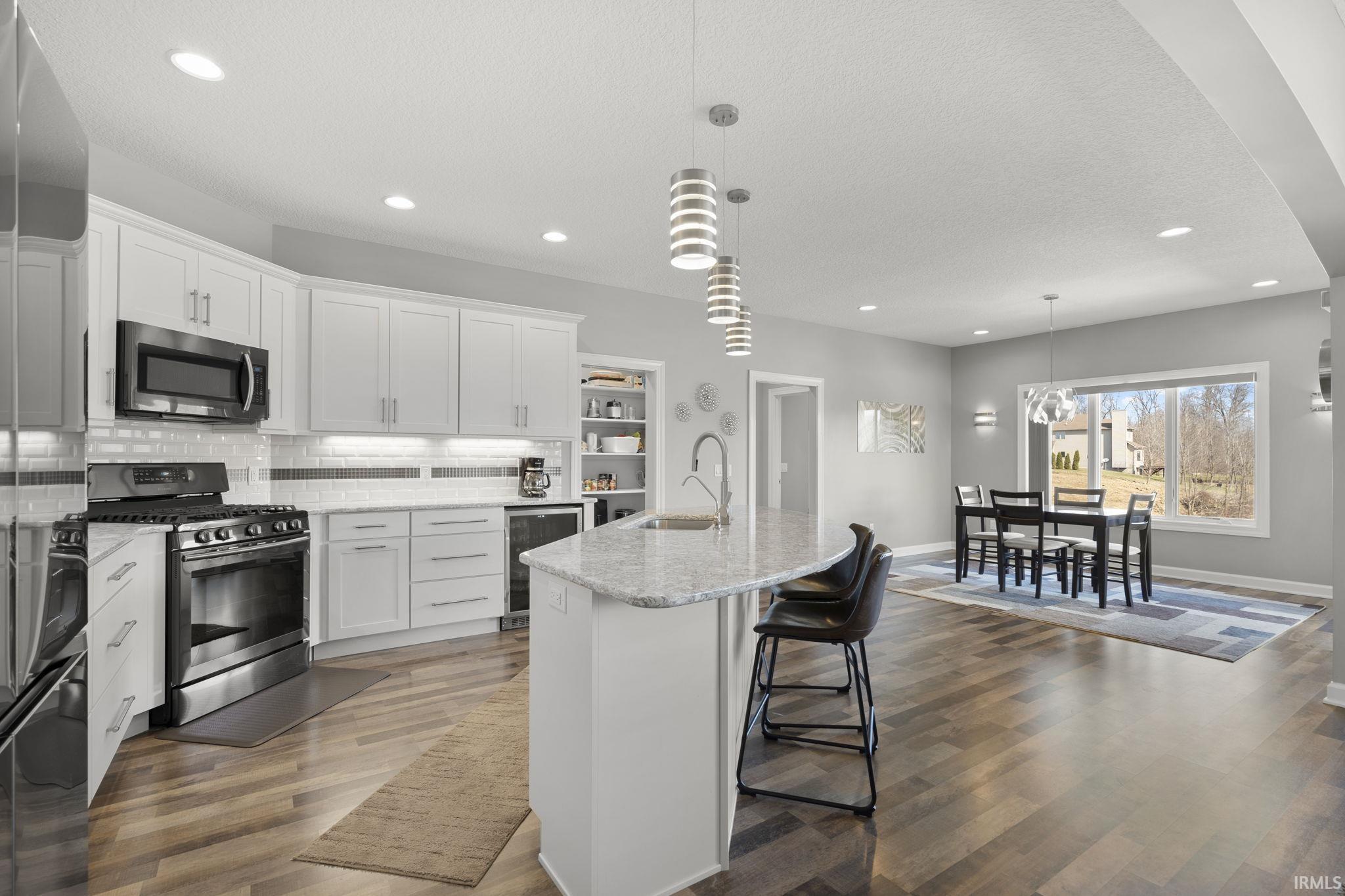 Kitchen with stainless steel appliances, recessed lighting, white cabinetry, a breakfast bar area, and pendant lighting