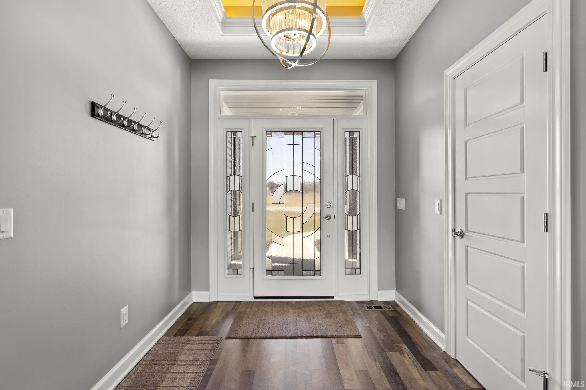Foyer entrance featuring a chandelier and dark wood-style flooring