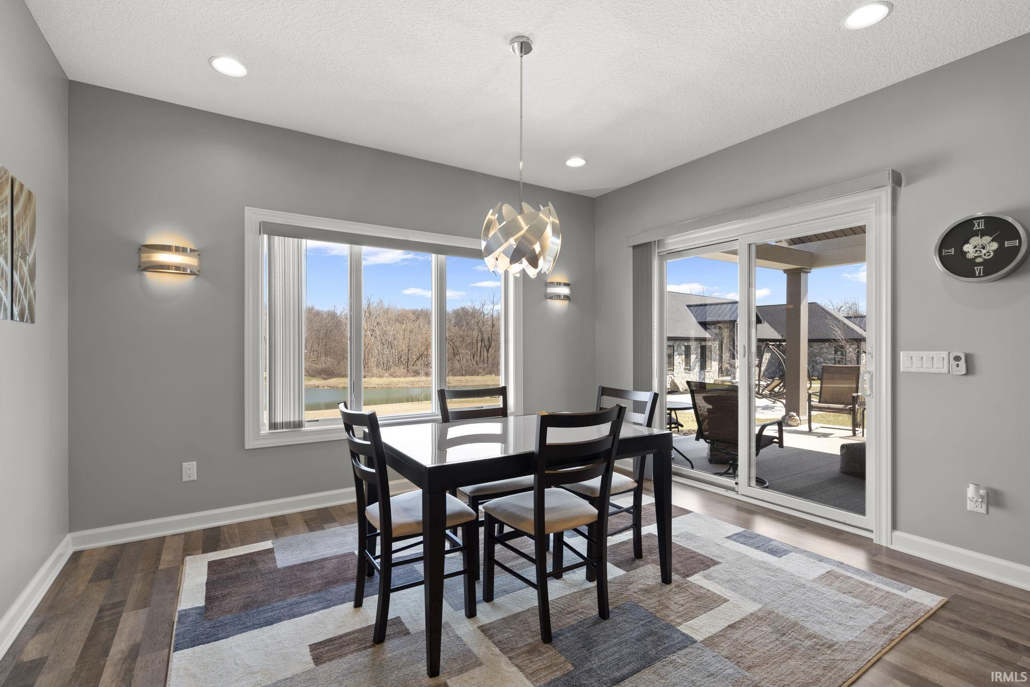 Dining room featuring plenty of natural light, dark wood finished floors, a water view, recessed lighting, and a textured ceiling
