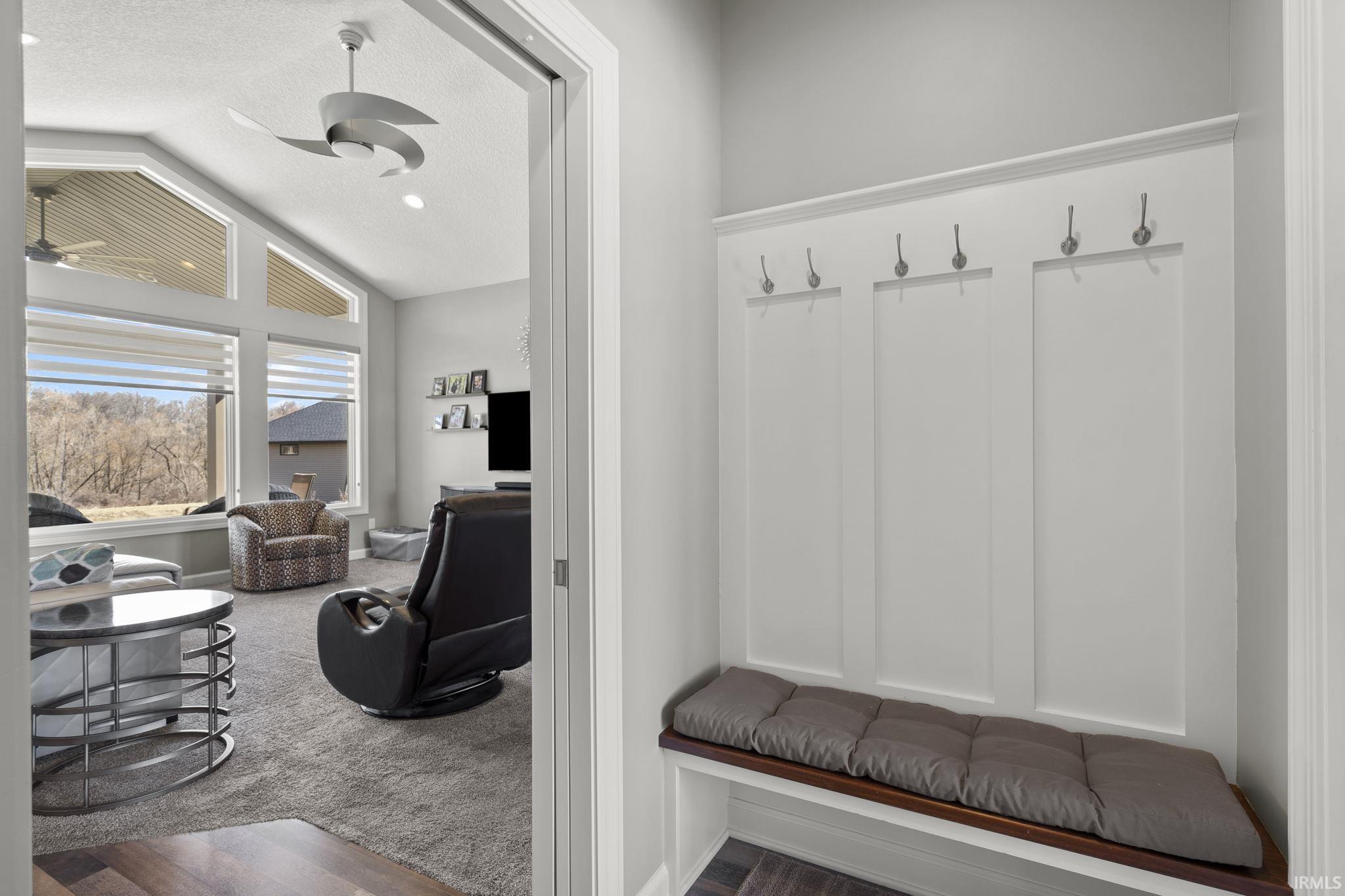 Mudroom featuring vaulted ceiling, dark carpet, a textured ceiling, and a ceiling fan