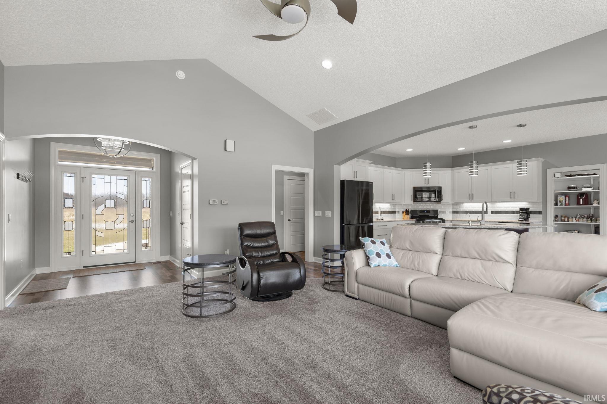 Living room with arched walkways, a ceiling fan, high vaulted ceiling, recessed lighting, and a textured ceiling