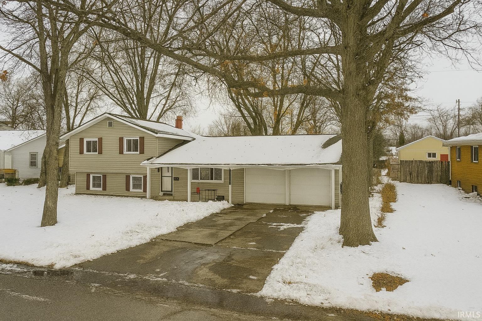 Tri-level home featuring a chimney, an attached garage, and driveway