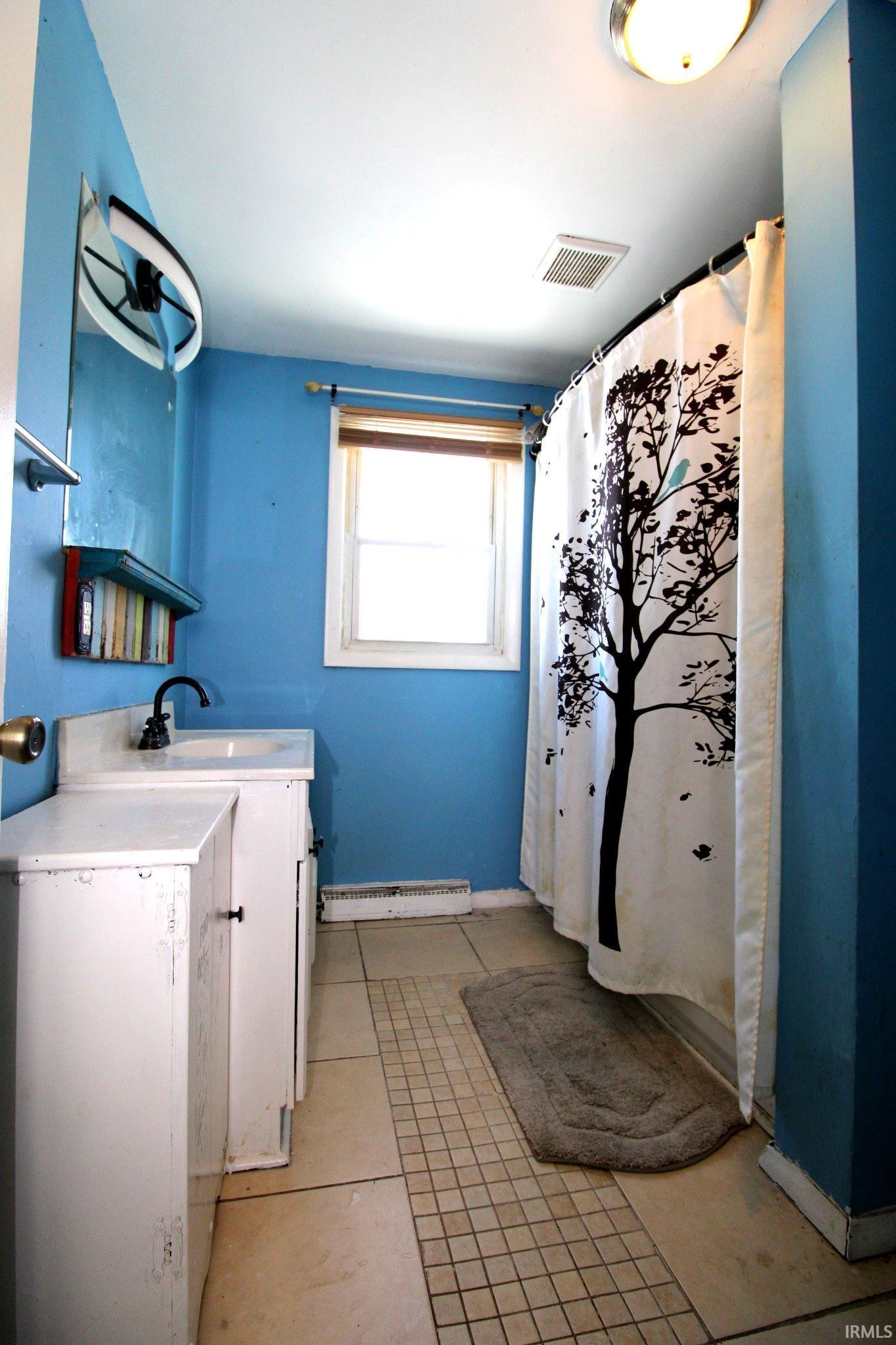 Laundry room with a baseboard heating unit and light tile patterned floors