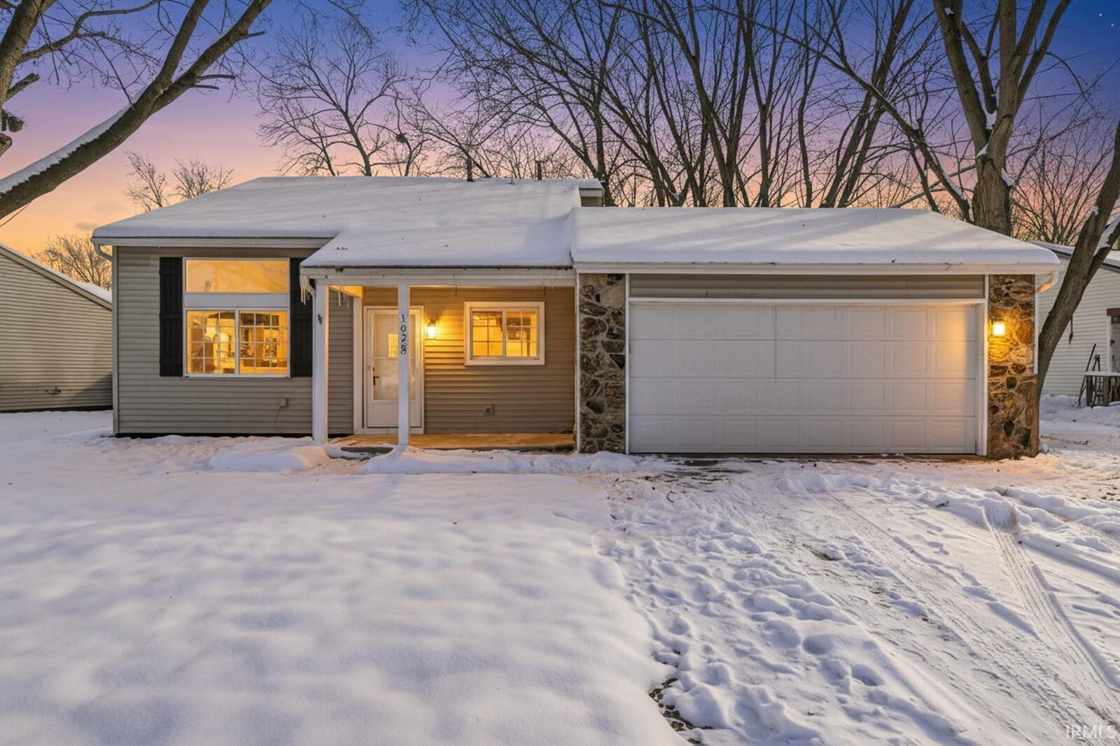 View of front of home with stone siding and an attached garage