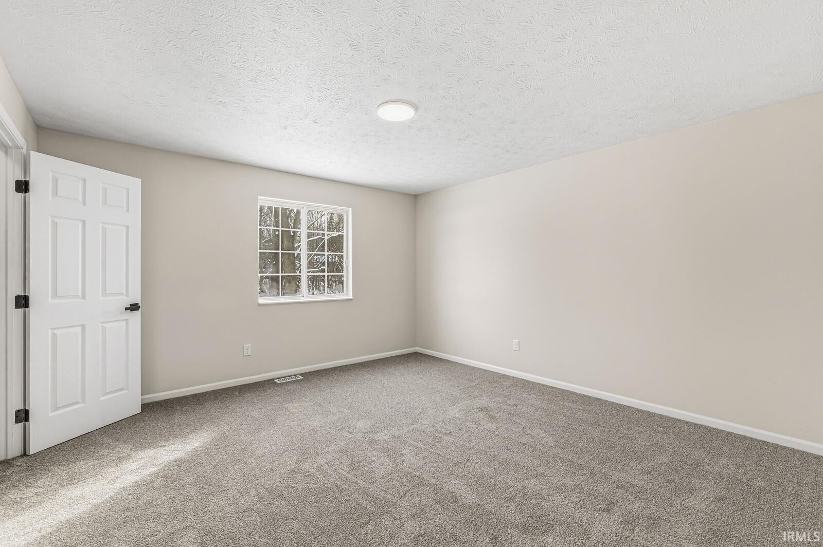 Unfurnished room with a textured ceiling and carpet