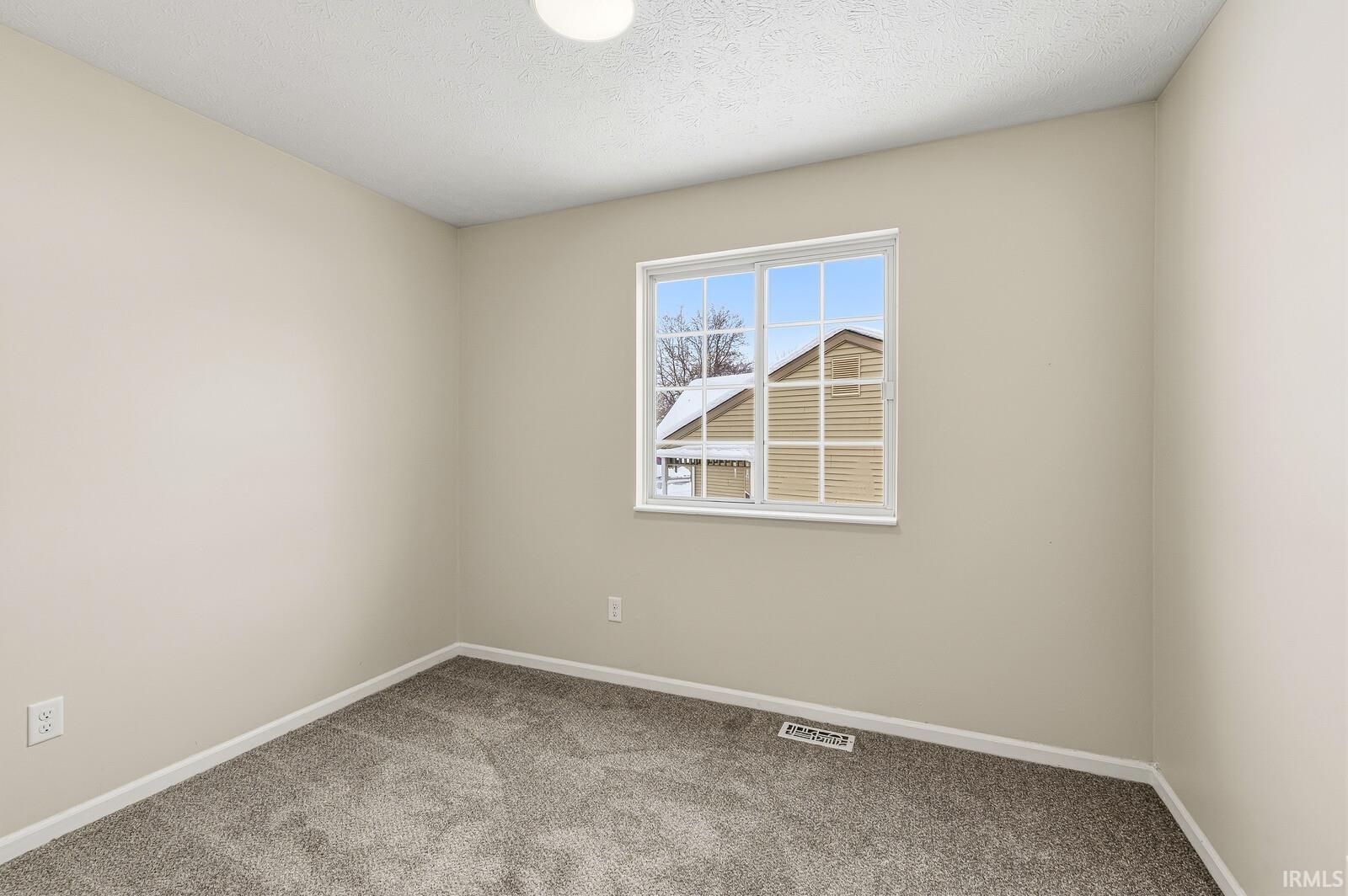 Carpeted spare room with baseboards and a textured ceiling