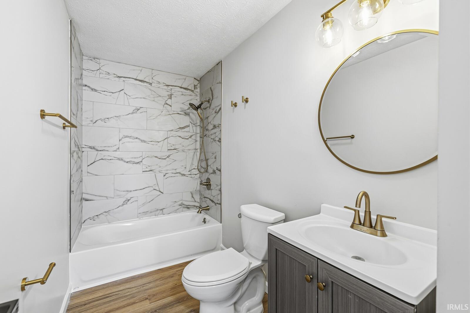 Full bathroom featuring tub / shower combination, vanity, a textured ceiling, and wood finished floors