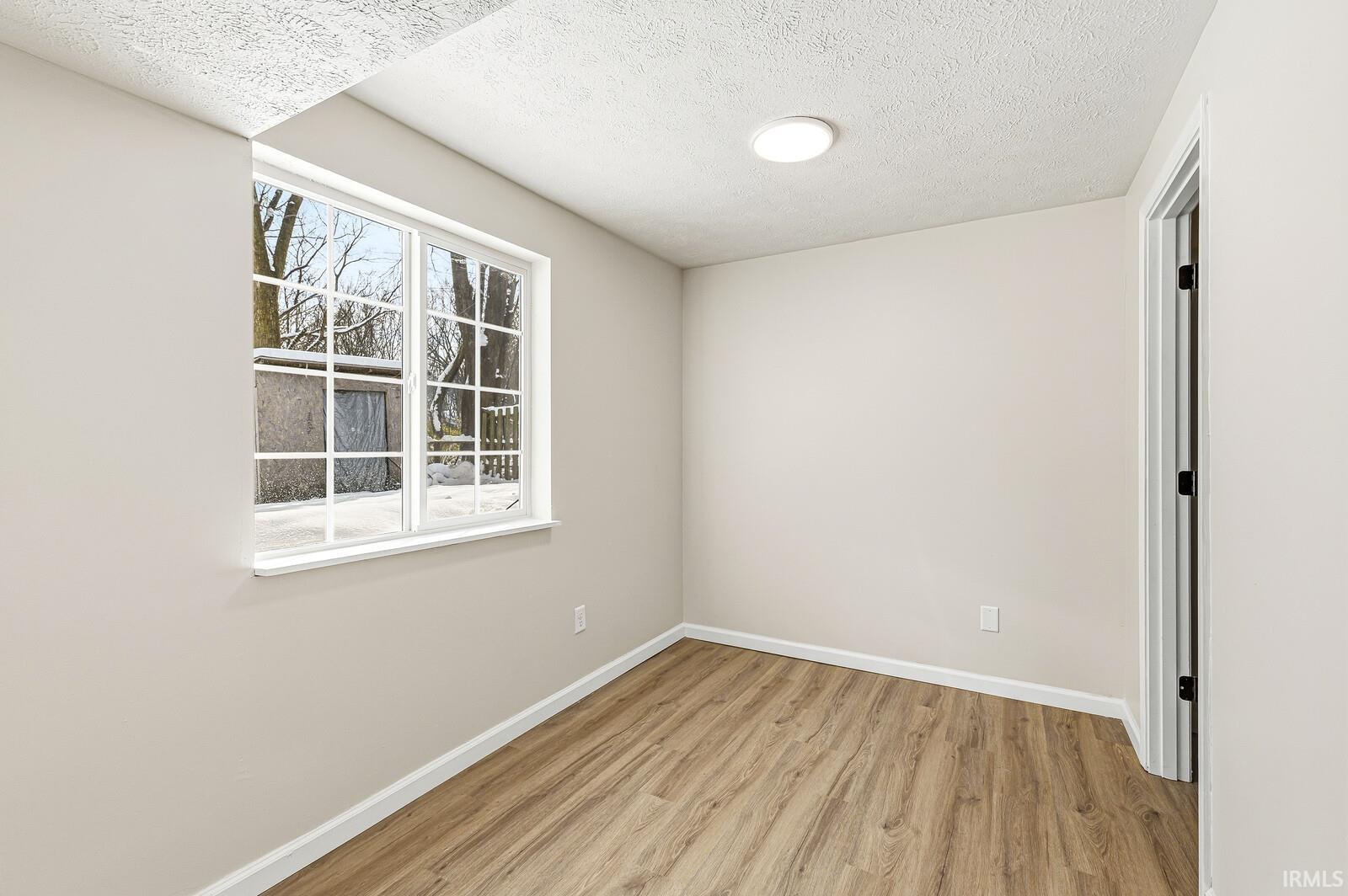 Spare room with a textured ceiling and light wood-type flooring