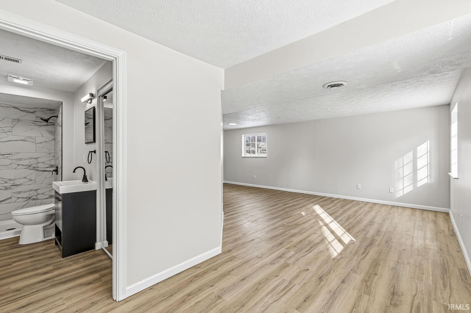 Unfurnished room with light wood-style floors and a textured ceiling